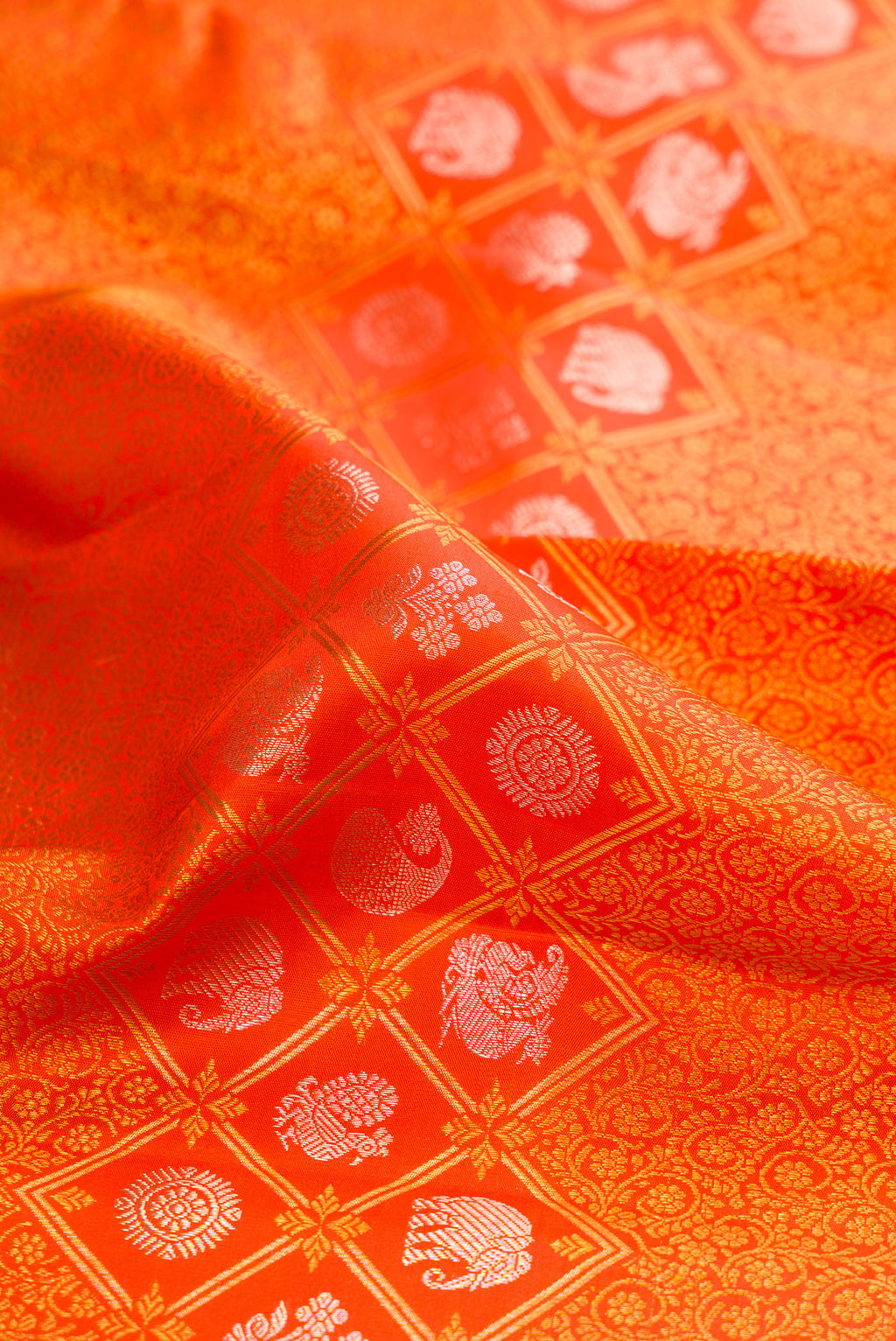 Close up of Orange Kanjivaram Silk Saree with Zari Brocade on the body and Zari Border.  displaying folds