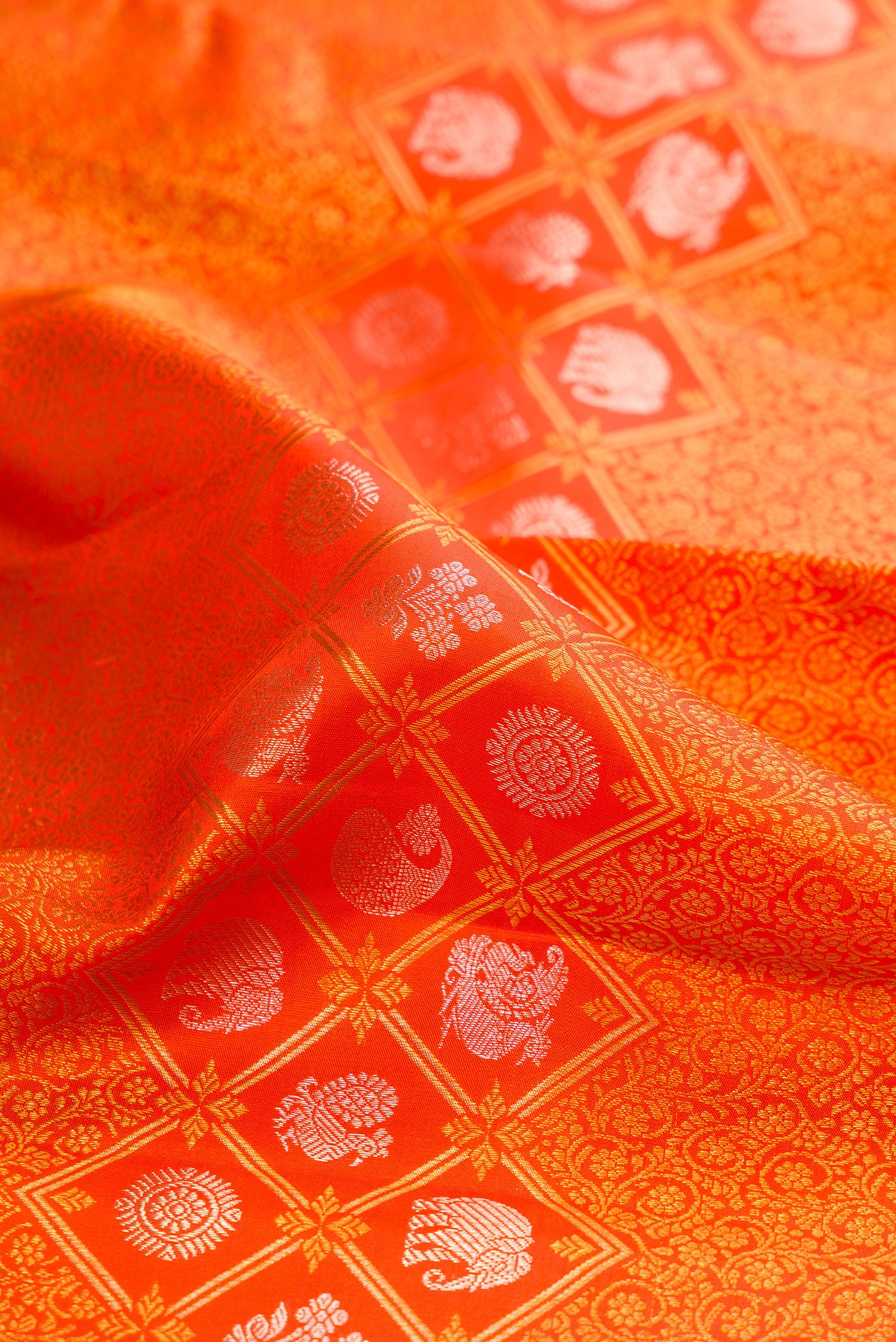 Close up of Orange Kanjivaram Silk Saree with Zari Brocade on the body and Zari Border.  displaying folds