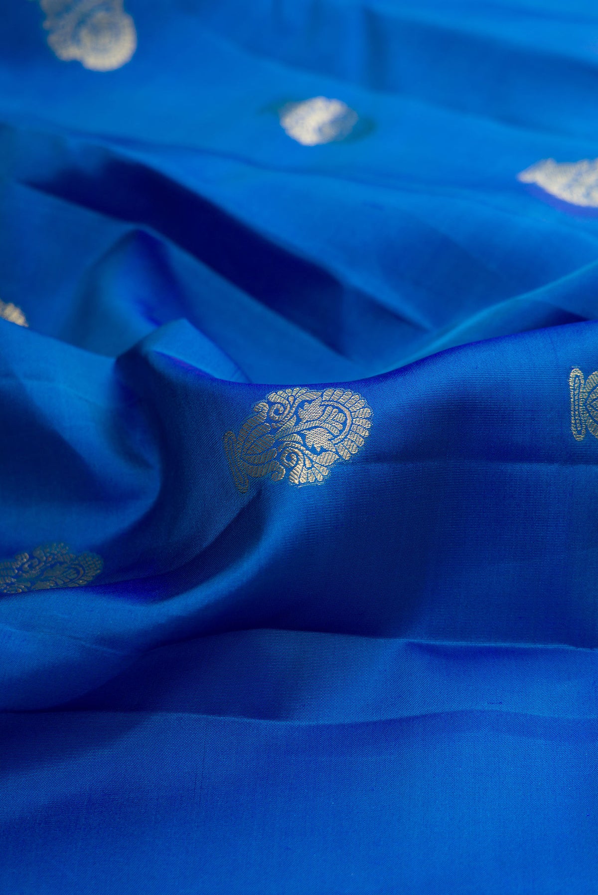 Close up of Pure Silk Peacock Blue Kanchipuram Saree with Zari Butta on the body and Fancy Border.  displaying folds