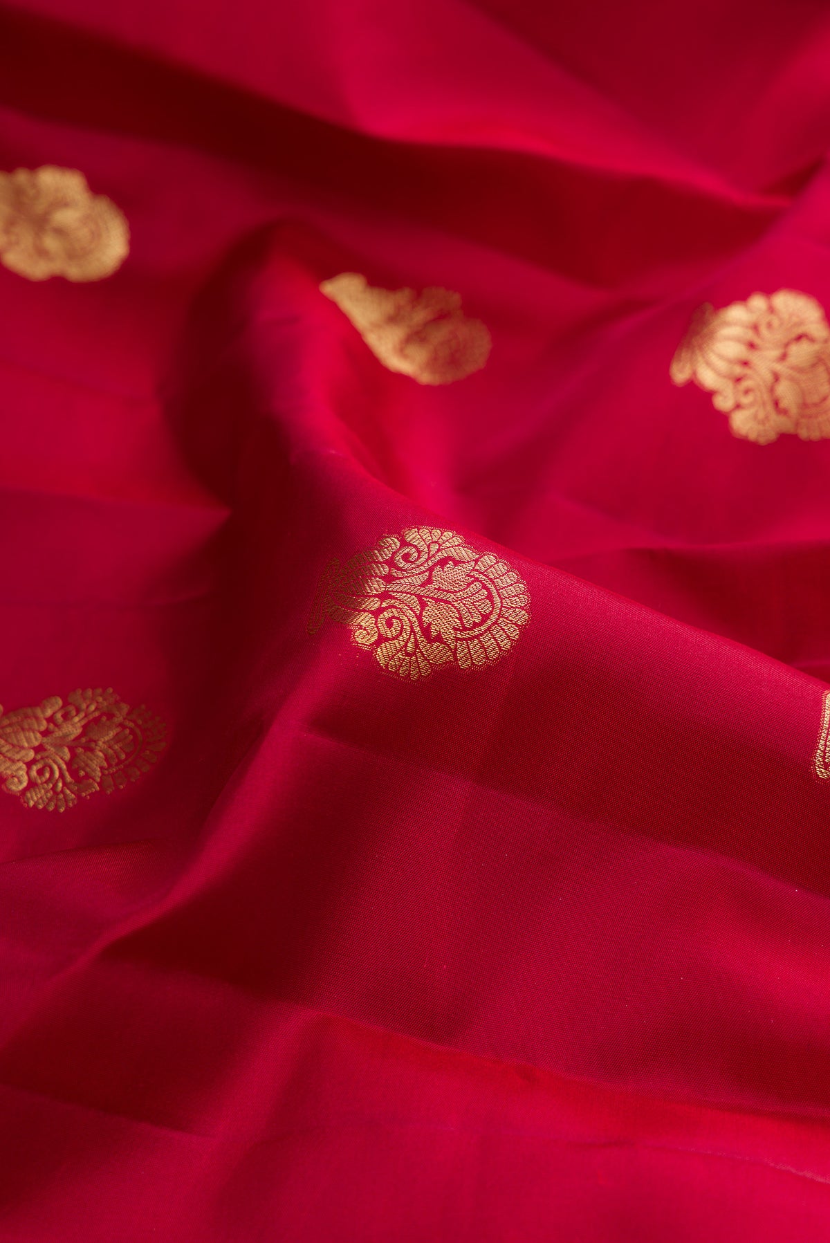 Close up of Pure Silk Maroon Kanchipuram Saree with Zari Butta on the body and Fancy Border.  displaying folds