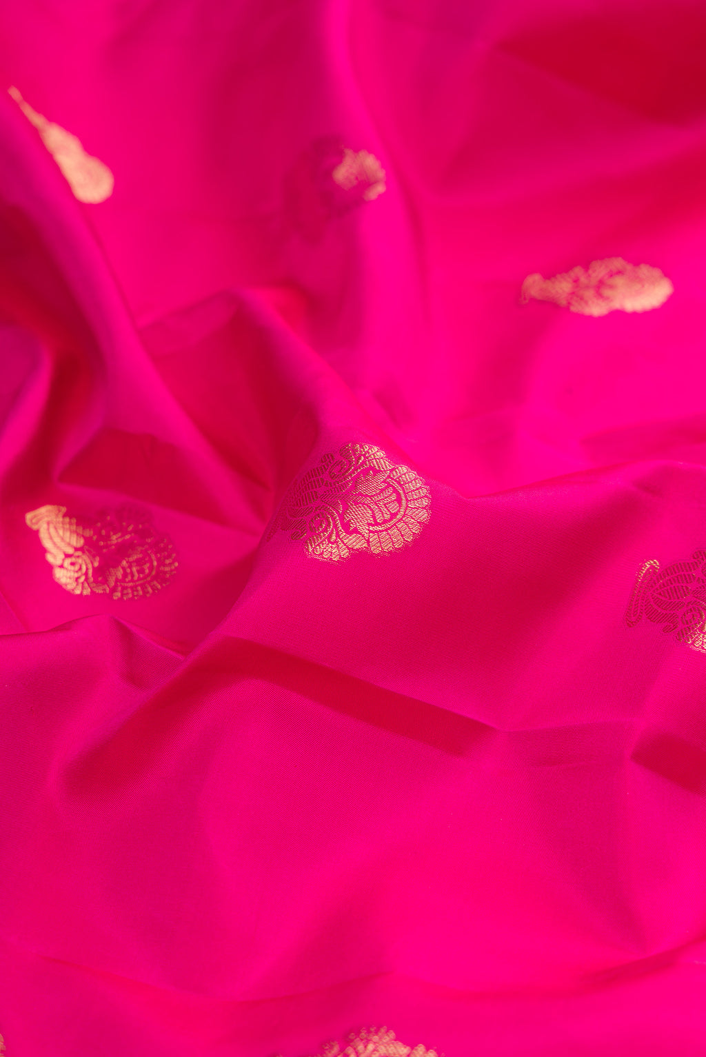 Close up of Pure Silk Rani Pink Kanchipuram Saree with Zari Butta on the body and Fancy Border.  displaying folds