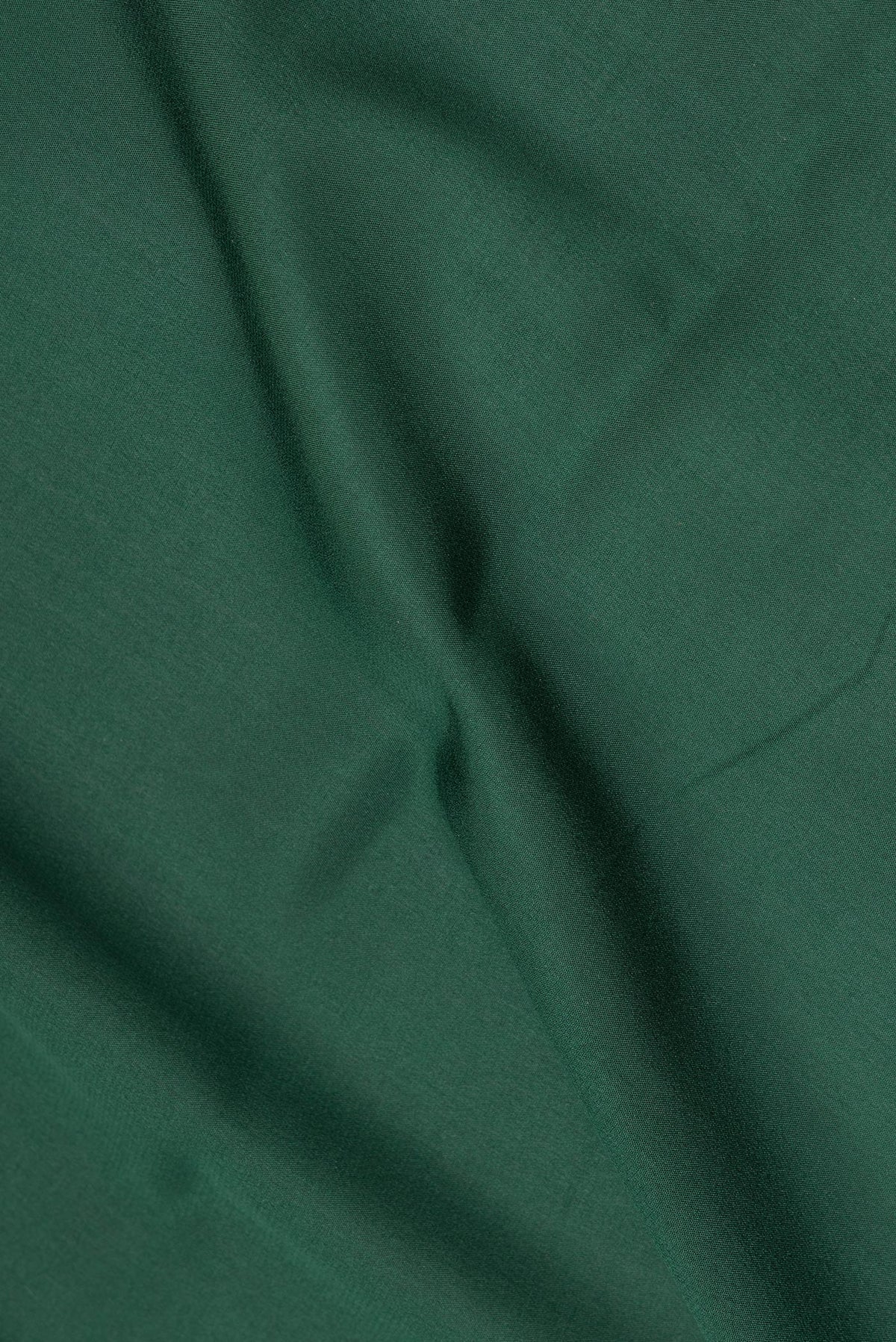 Close up of Bottle Green Mysore Crepe Saree with Plain Body and Zari Border.  displaying folds