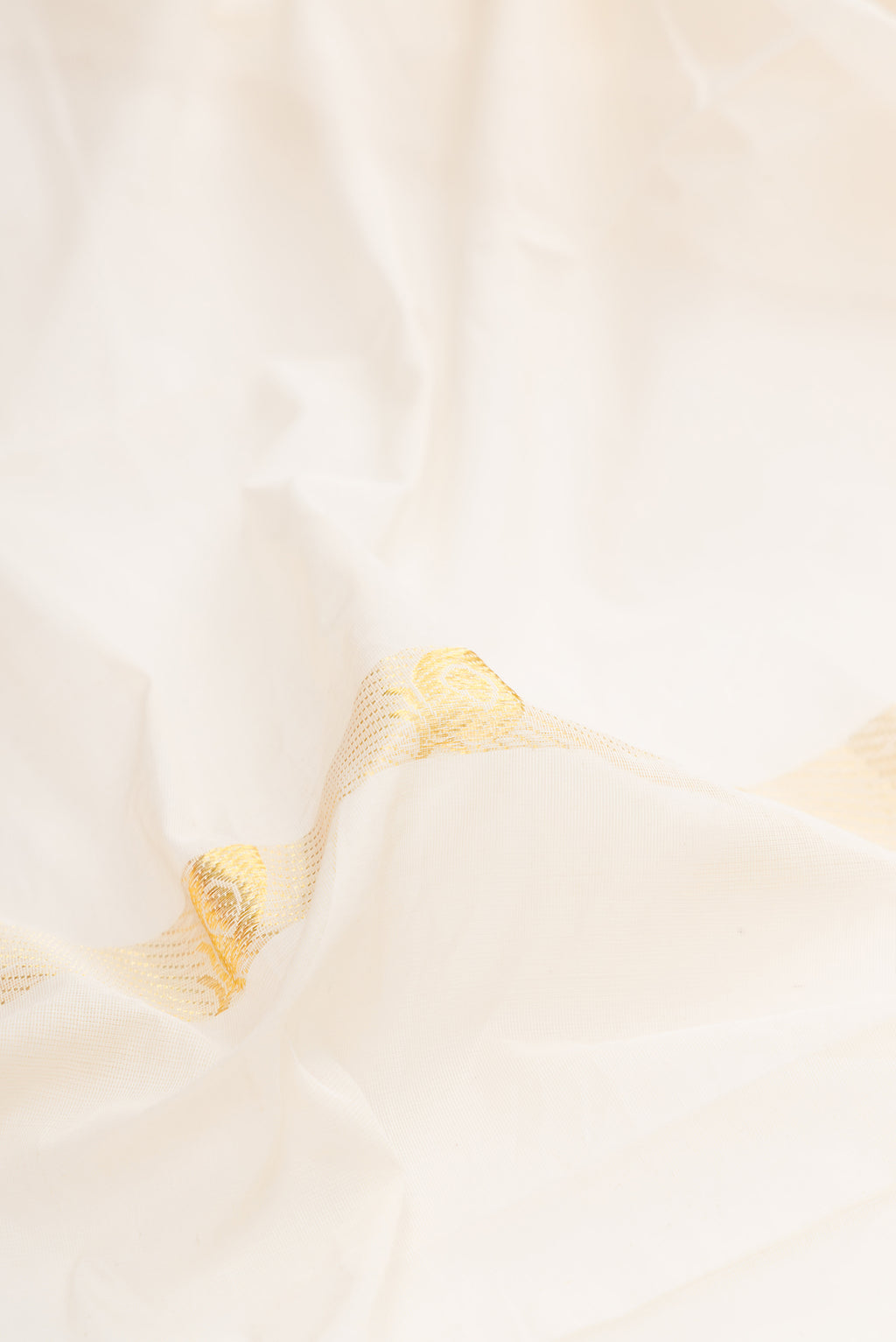 Close up of Off White Kerala Cotton Saree with Zari Butta on the body and Fancy Border.  displaying folds