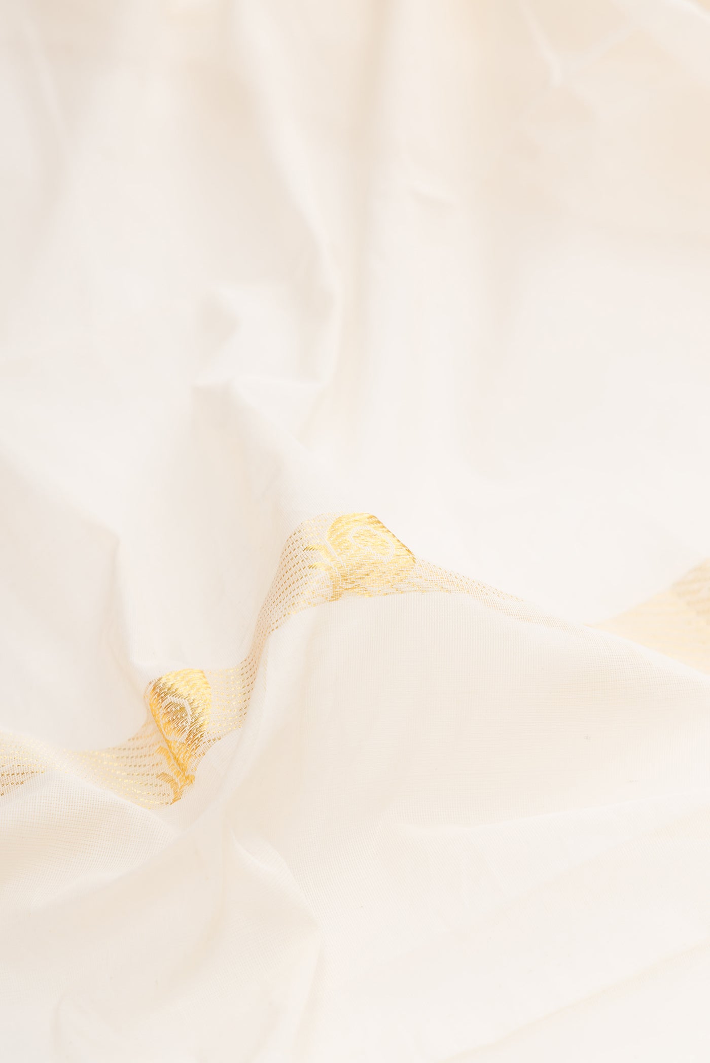Close up of Off White Kerala Cotton Saree with Zari Butta on the body and Fancy Border.  displaying folds