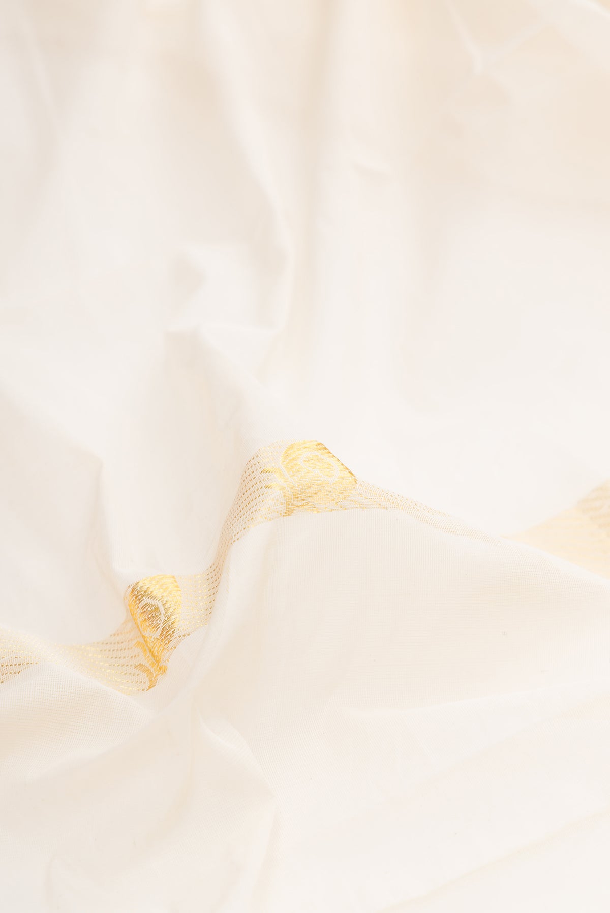 Close up of Off White Kerala Cotton Saree with Zari Butta on the body and Fancy Border.  displaying folds