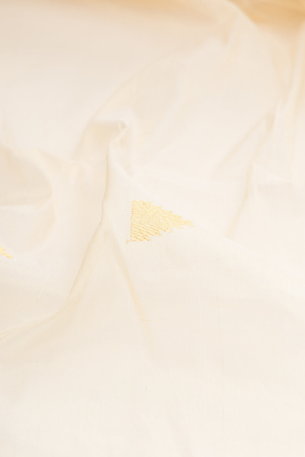 Close up of Off White Kerala Cotton Saree with Zari Butta on the body and Zari Border.  displaying folds
