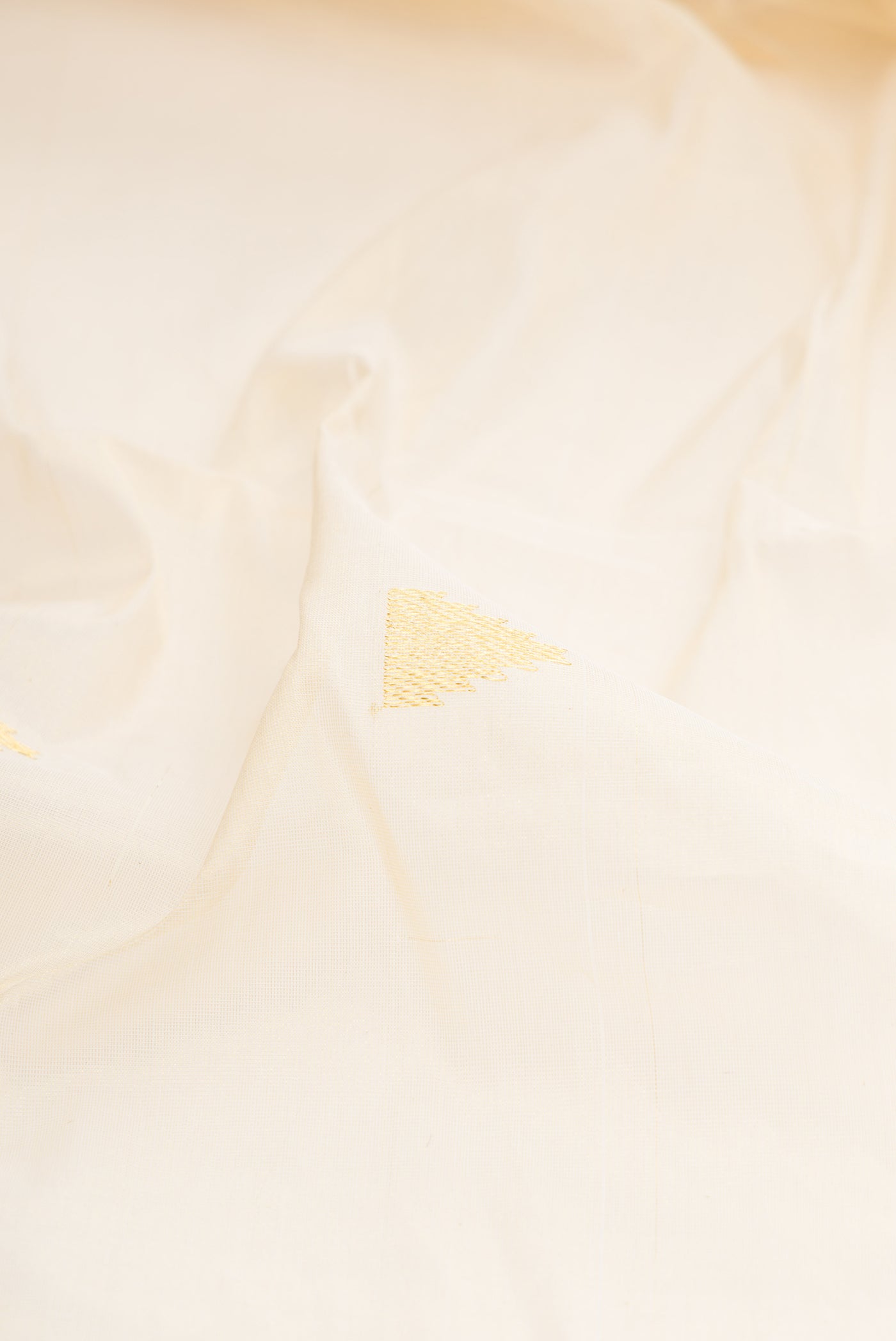Close up of Off White Kerala Cotton Saree with Zari Butta on the body and Zari Border.  displaying folds