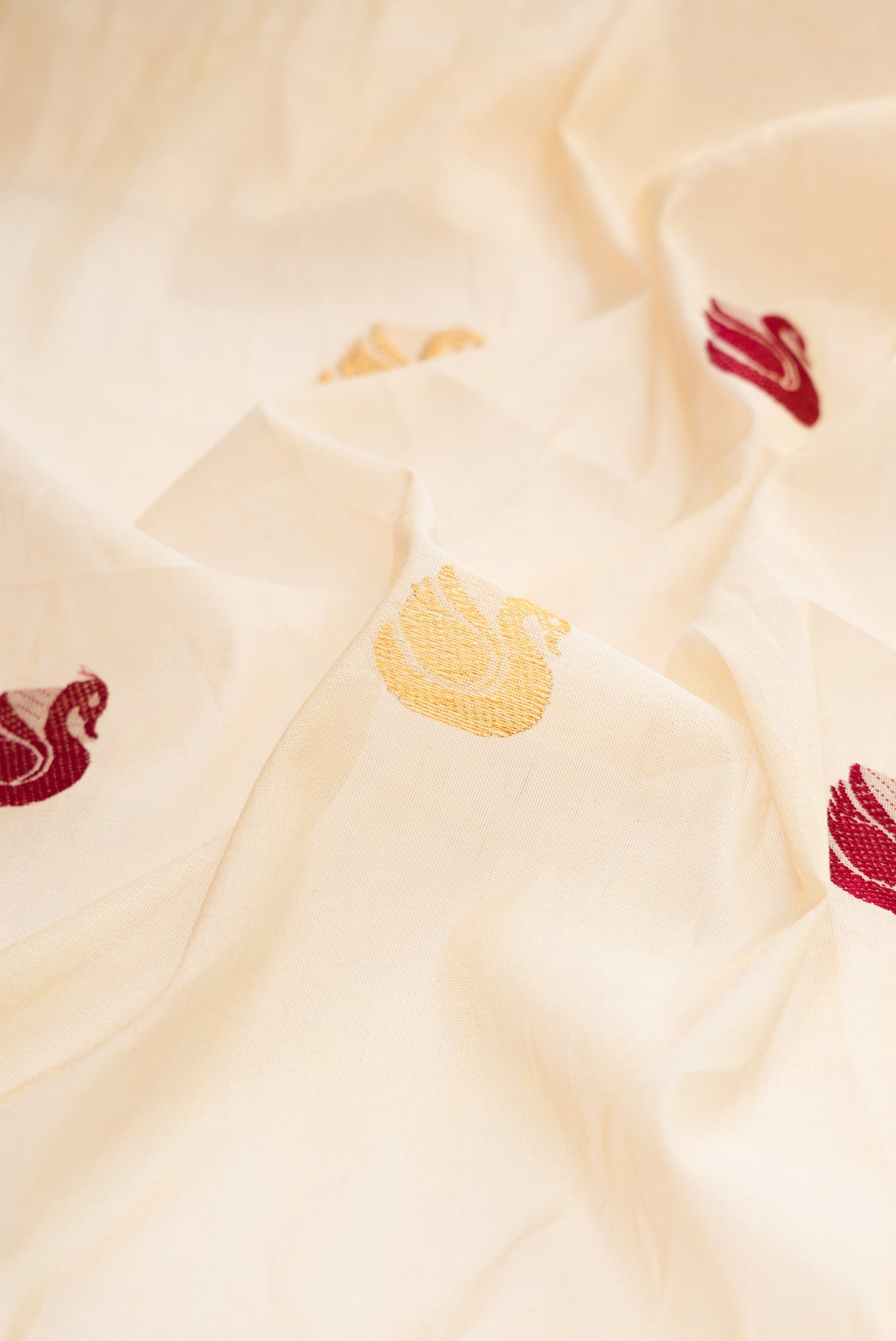 Close up of Off White Kerala Cotton Saree with Zari And Thread Butta on the body and Zari Border.  displaying folds