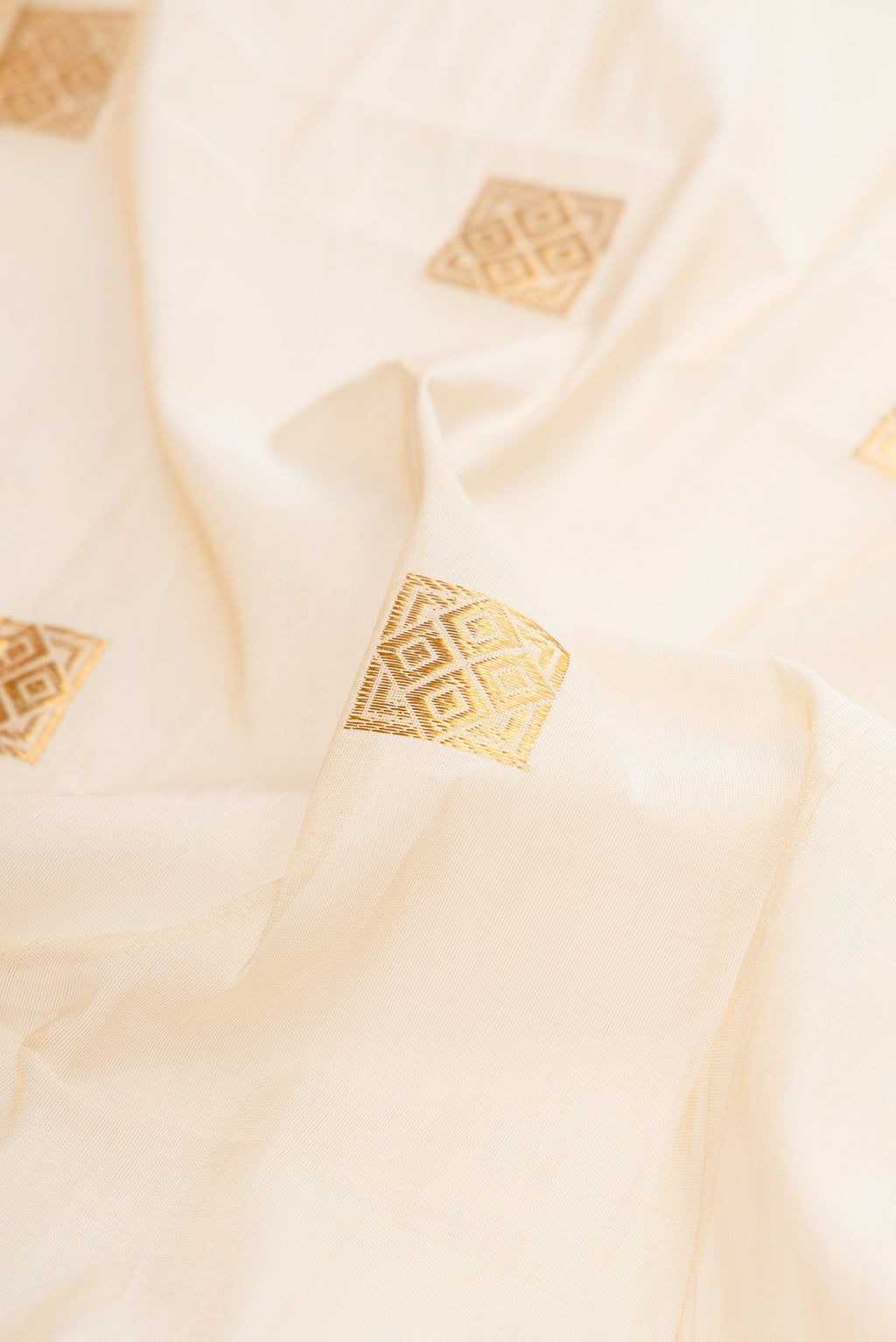 Close up of Off White Kerala Cotton Saree with Zari Butta on the body and Zari Border.  displaying folds