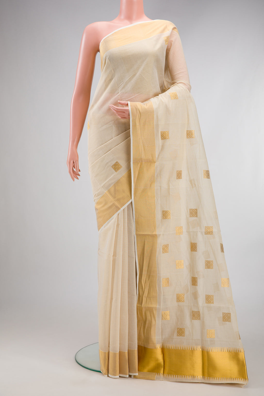 Off White Kerala Cotton Saree with Zari Butta on the body and Zari Border.  displayed on a mannequin