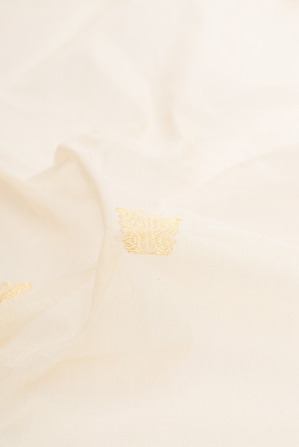 Close up of Off White Kerala Cotton Saree with Zari Butta on the body and Zari Border.  displaying folds