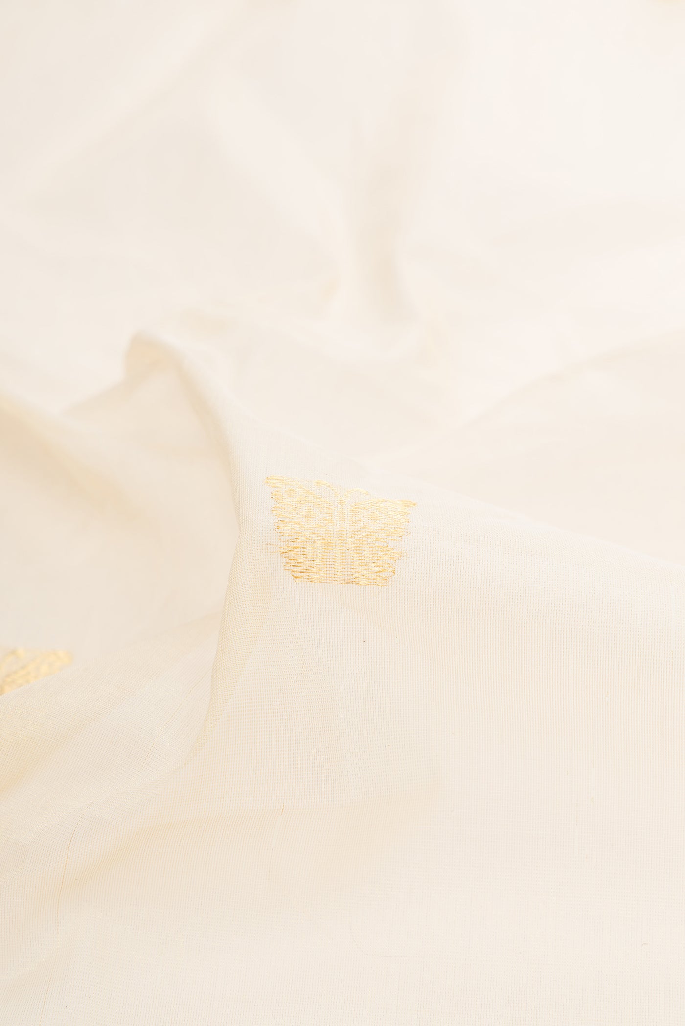 Close up of Off White Kerala Cotton Saree with Zari Butta on the body and Zari Border.  displaying folds