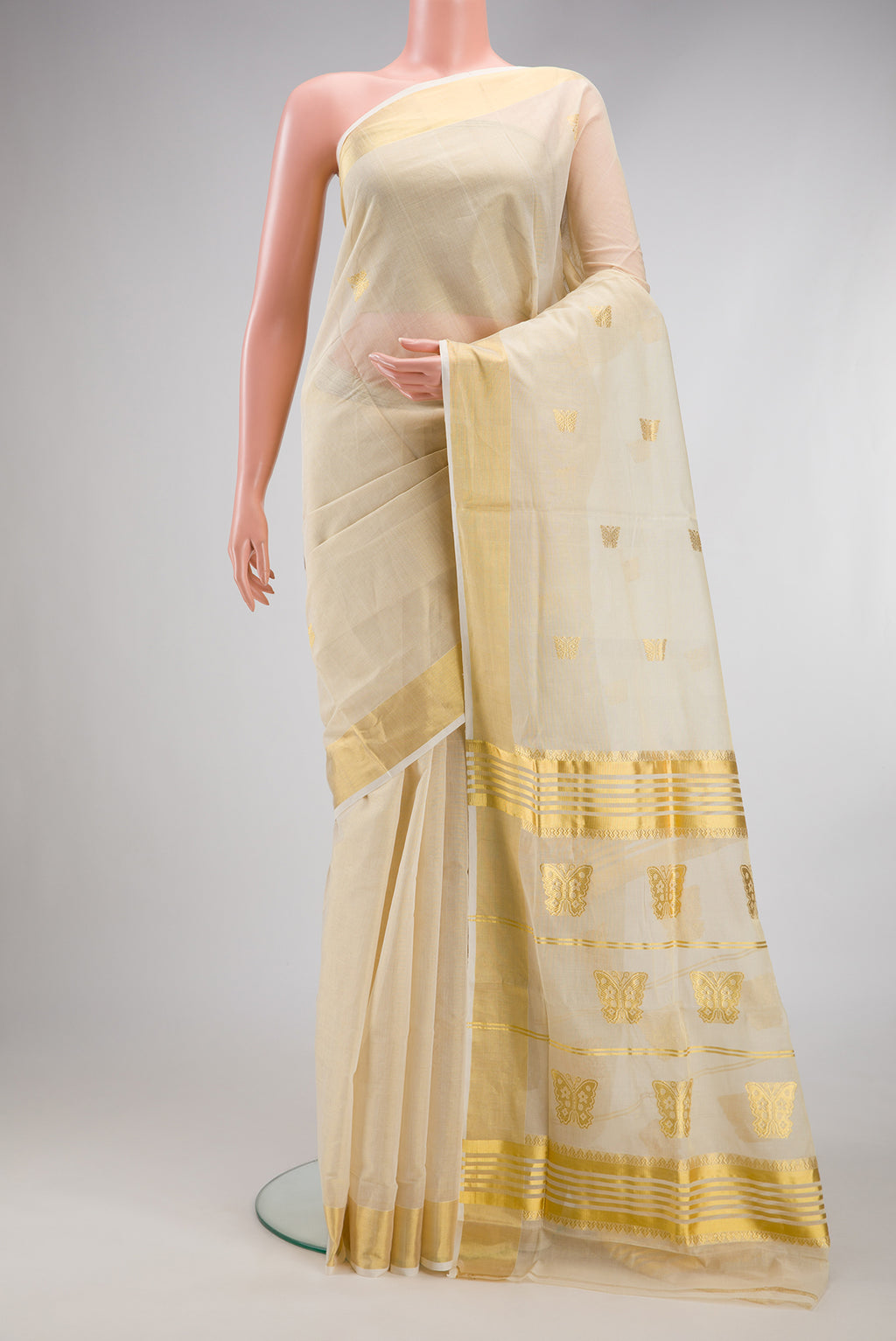 Off White Kerala Cotton Saree with Zari Butta on the body and Zari Border.  displayed on a mannequin