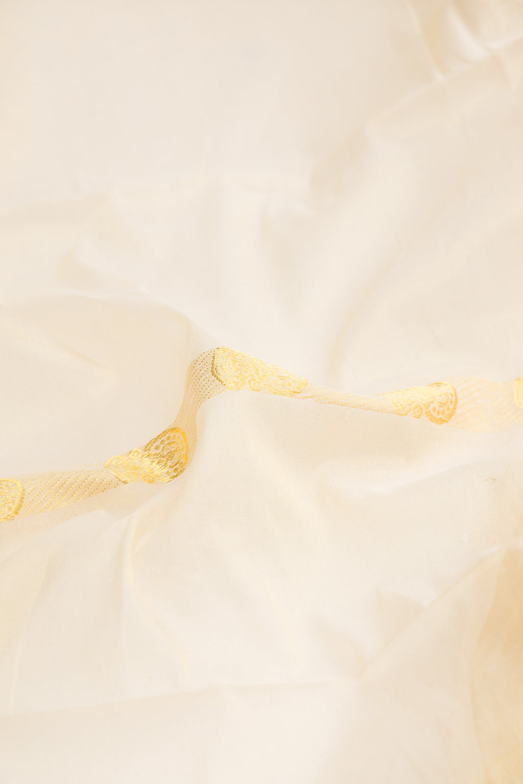 Close up of Pure Silk Off White Kerala Cotton Saree with Zari Butta on the body and Zari Border.  displaying folds