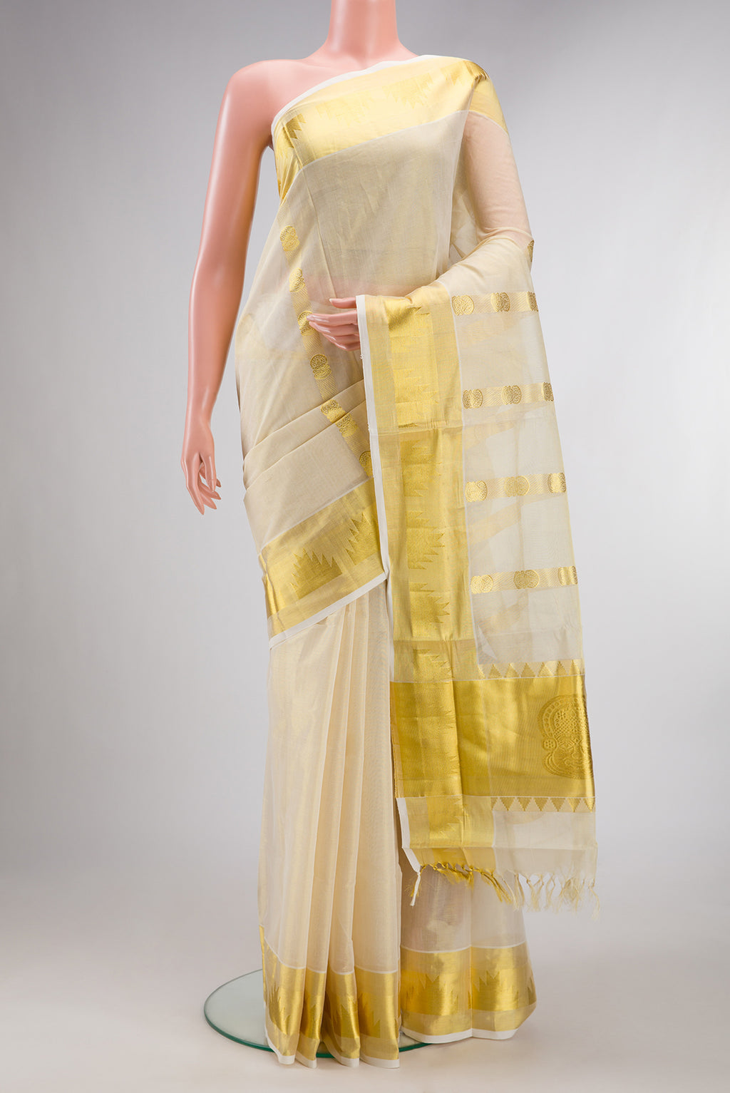 Pure Silk Off White Kerala Cotton Saree with Zari Butta on the body and Zari Border.  displayed on a mannequin