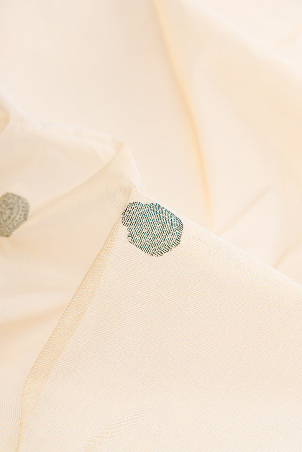Close up of Pure Silk Off White Kerala Cotton Saree with Thread Butta on the body and Zari Border.  displaying folds