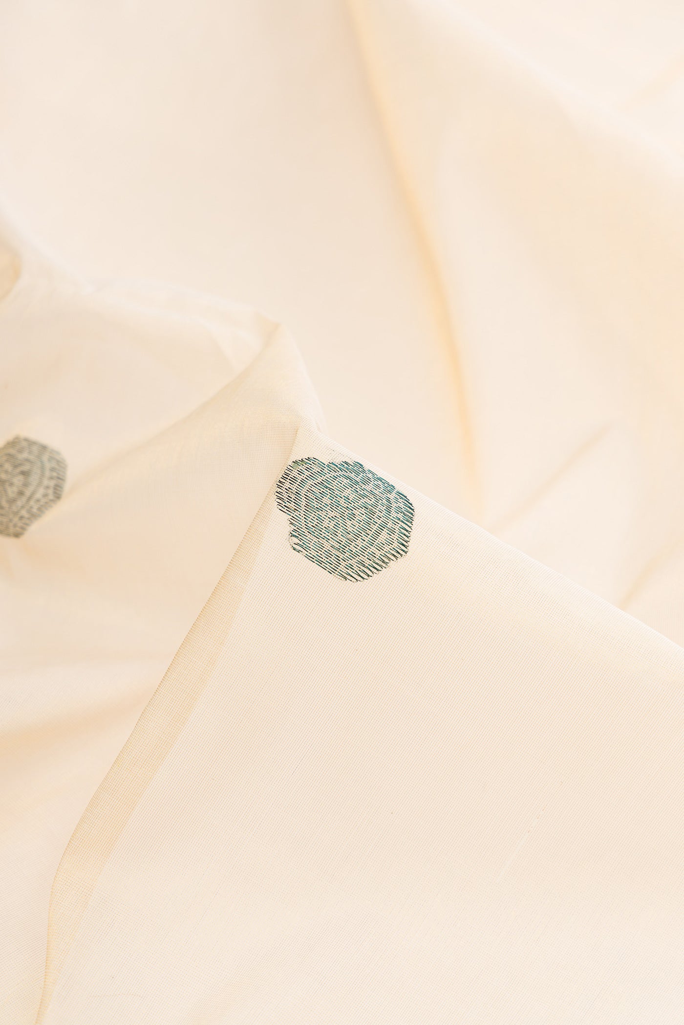 Close up of Pure Silk Off White Kerala Cotton Saree with Thread Butta on the body and Zari Border.  displaying folds