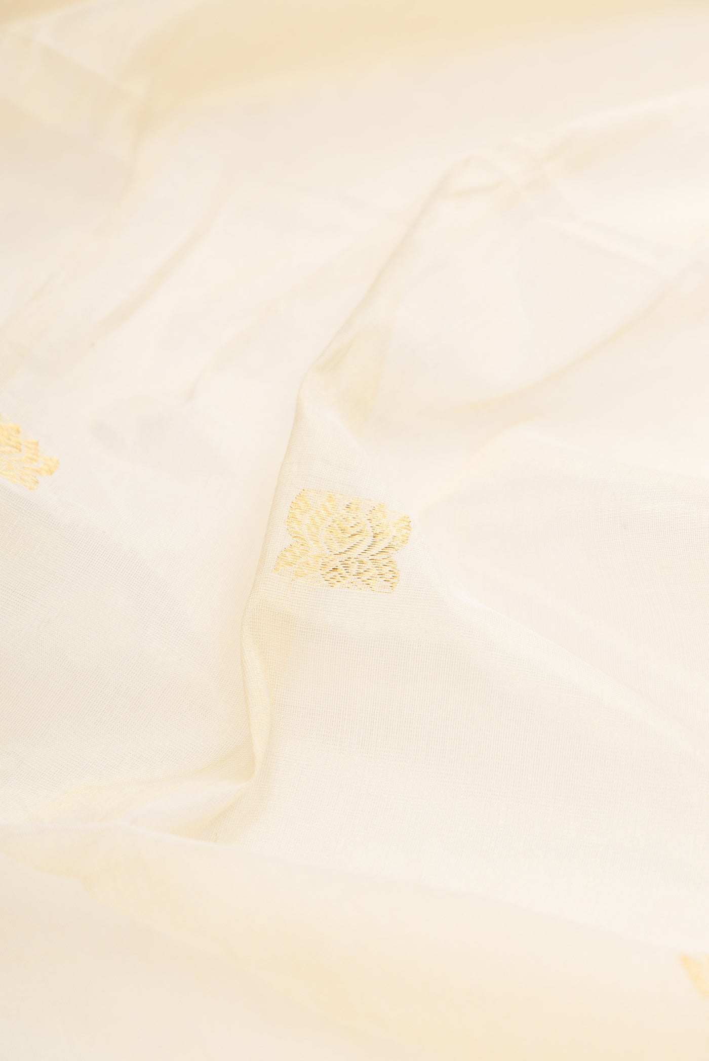 Close up of Off White Kerala Cotton Saree with Zari Butta on the body and Zari Border.  displaying folds