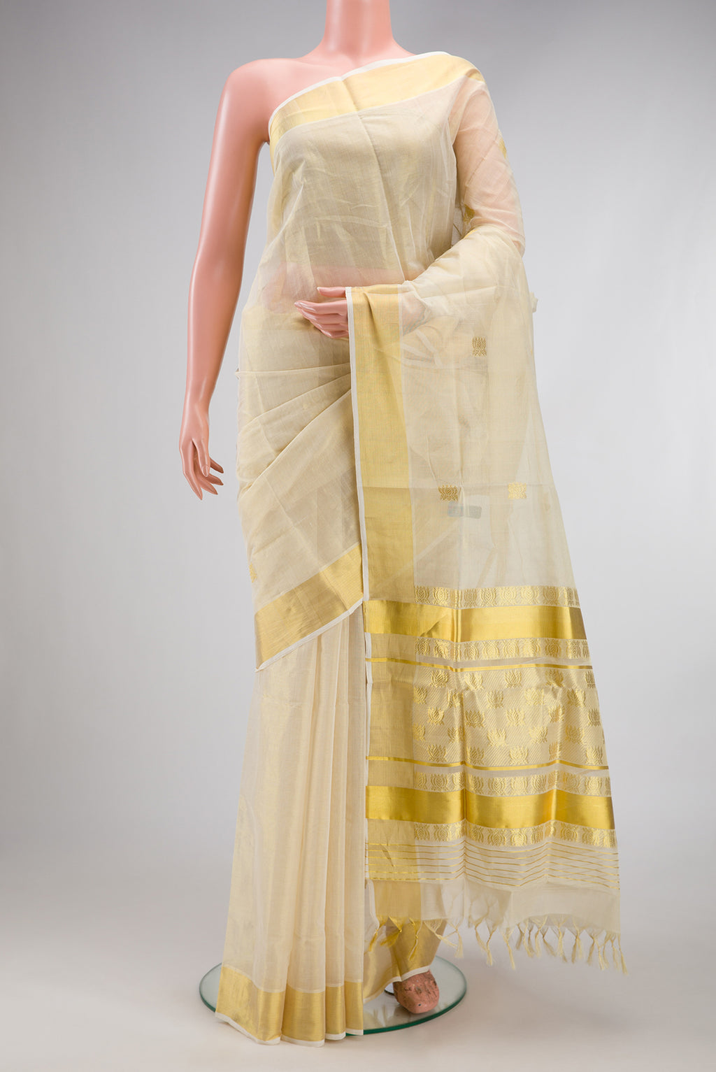 Off White Kerala Cotton Saree with Zari Butta on the body and Zari Border.  displayed on a mannequin