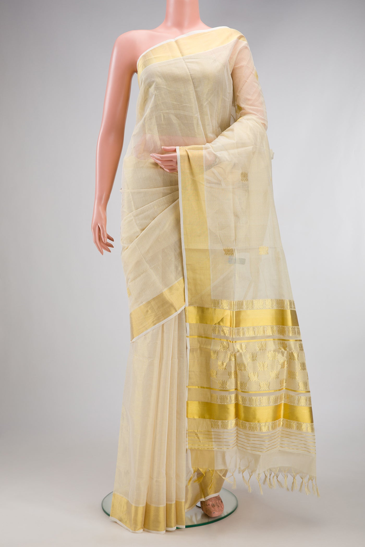 Off White Kerala Cotton Saree with Zari Butta on the body and Zari Border.  displayed on a mannequin