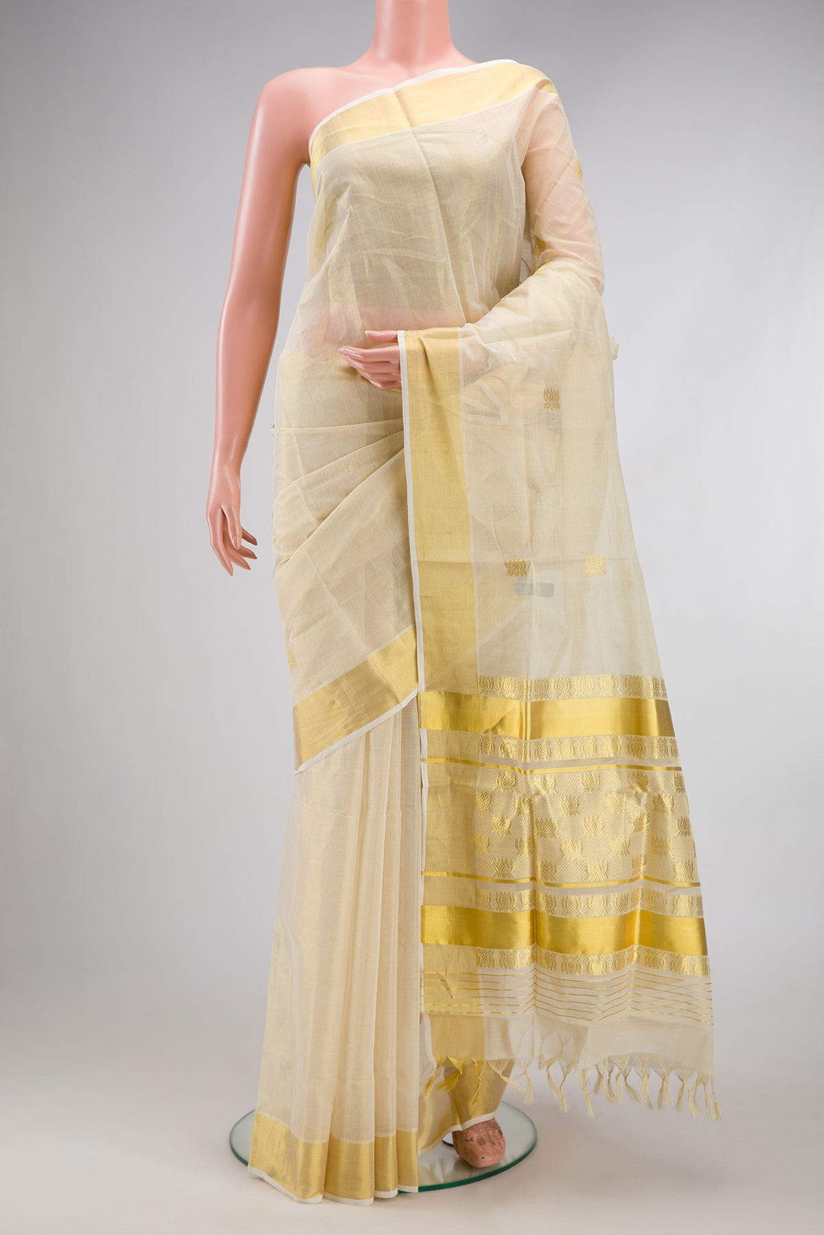 Off White Kerala Cotton Saree with Zari Butta on the body and Zari Border.  displayed on a mannequin