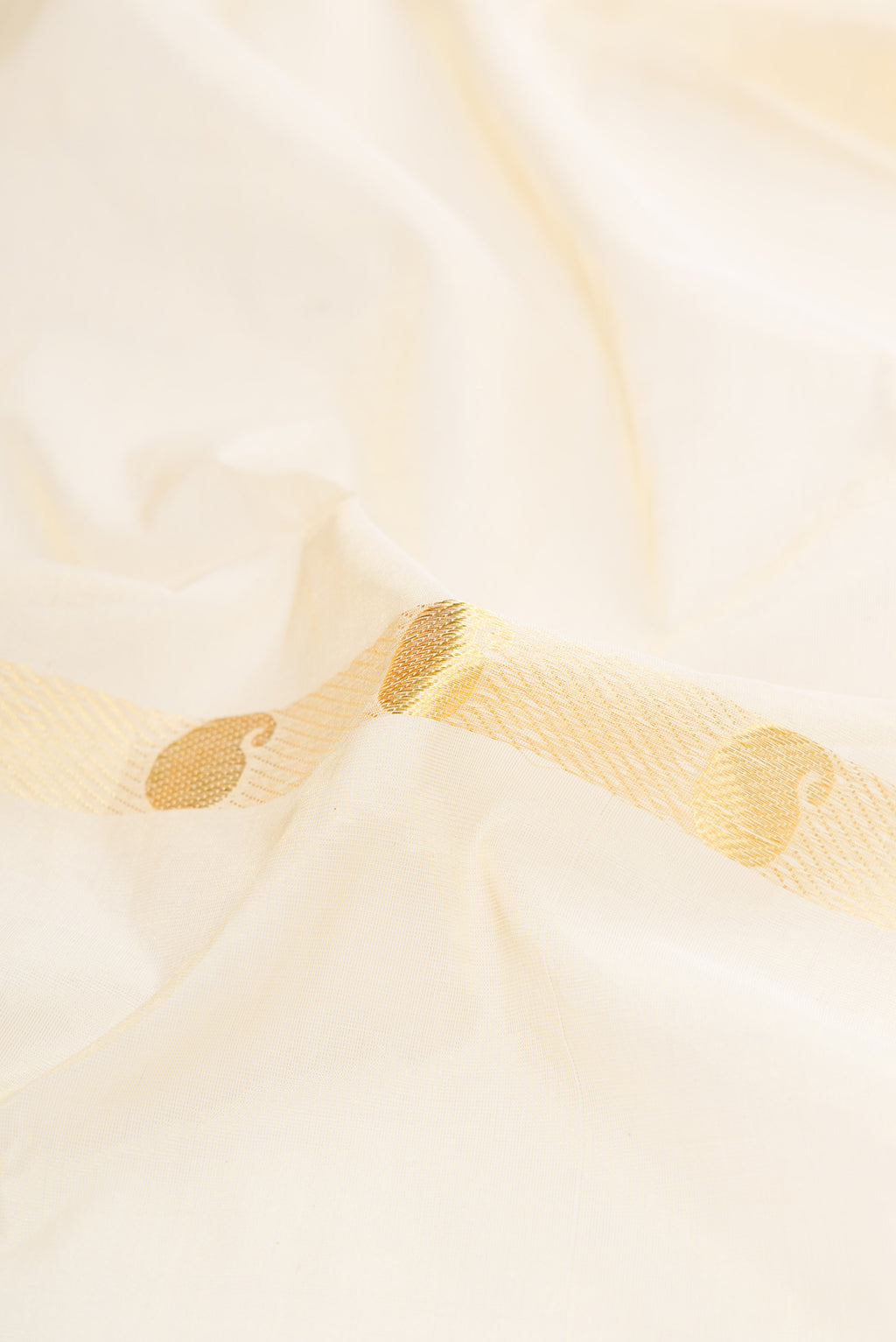 Close up of Off White Kerala Cotton Saree with Zari Butta on the body and Zari Border.  displaying folds