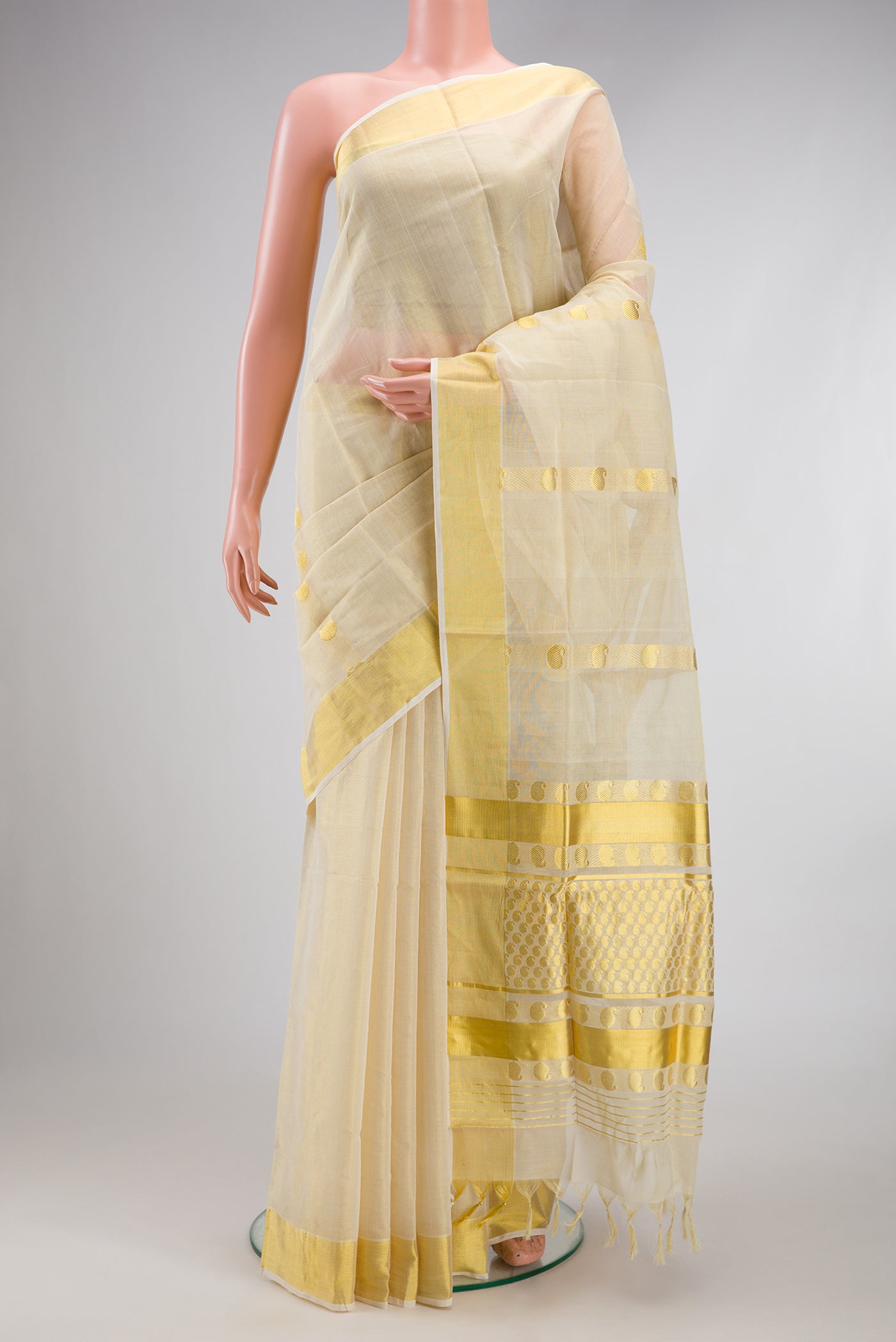 Off White Kerala Cotton Saree with Zari Butta on the body and Zari Border.  displayed on a mannequin