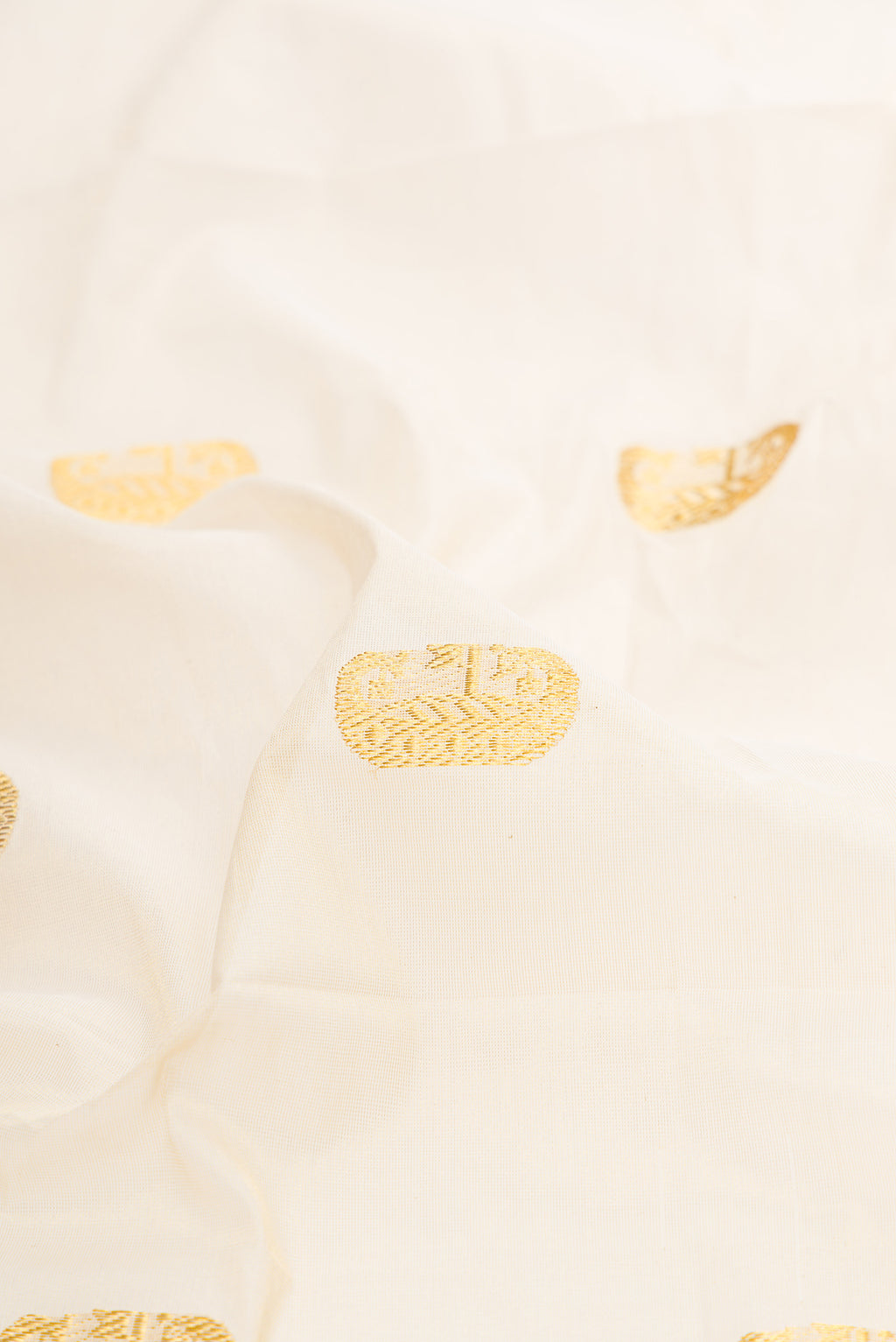Close up of Off White Kerala Cotton Saree with Zari Butta on the body and Temple Border.  displaying folds