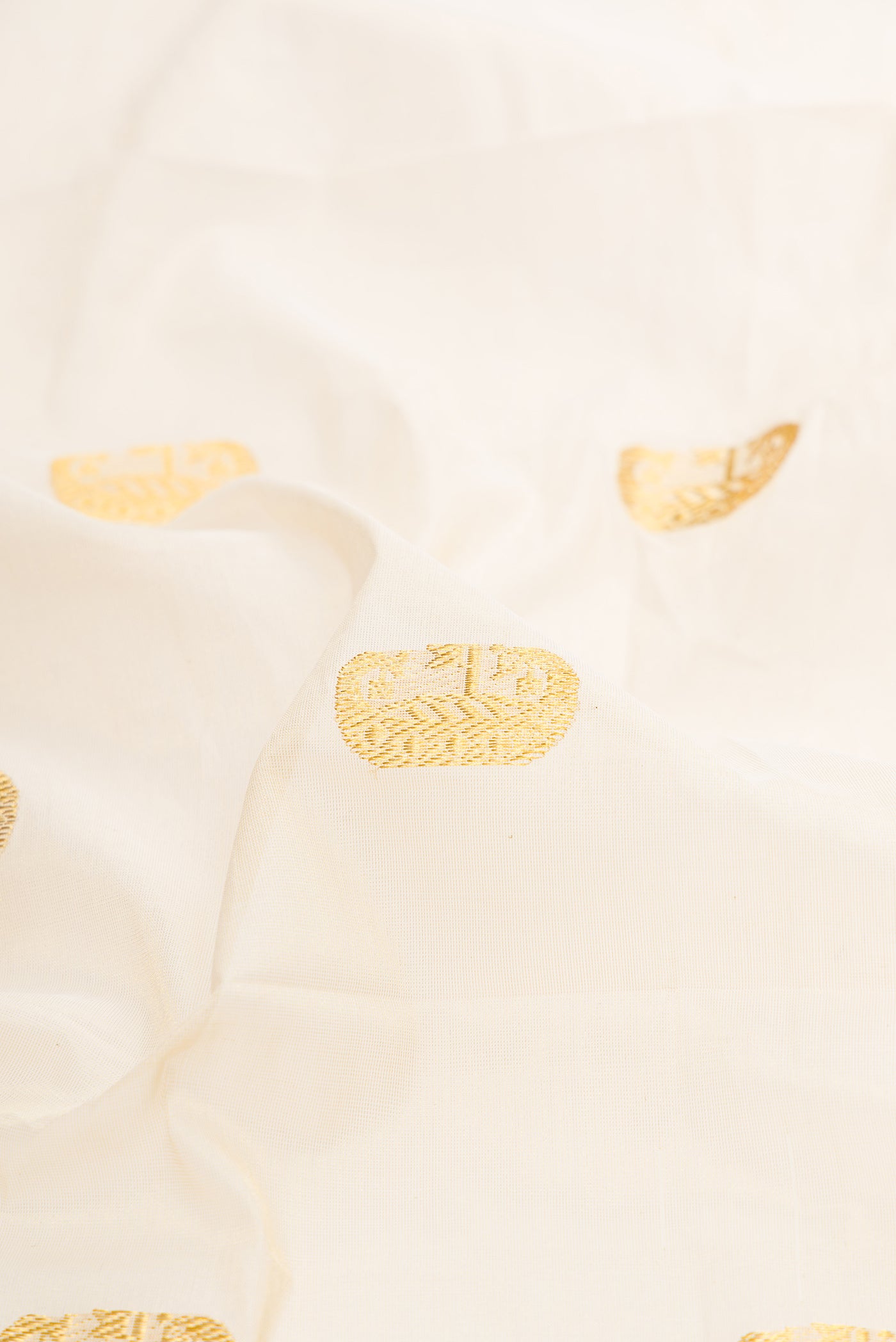 Close up of Off White Kerala Cotton Saree with Zari Butta on the body and Temple Border.  displaying folds