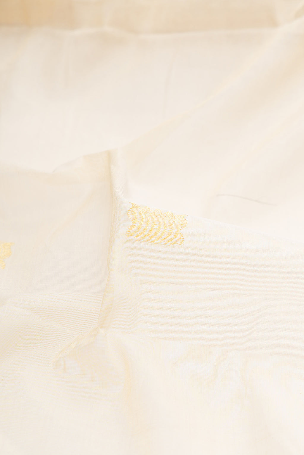 Close up of Off White Kerala Cotton Saree with Zari Butta on the body and Zari Border.  displaying folds