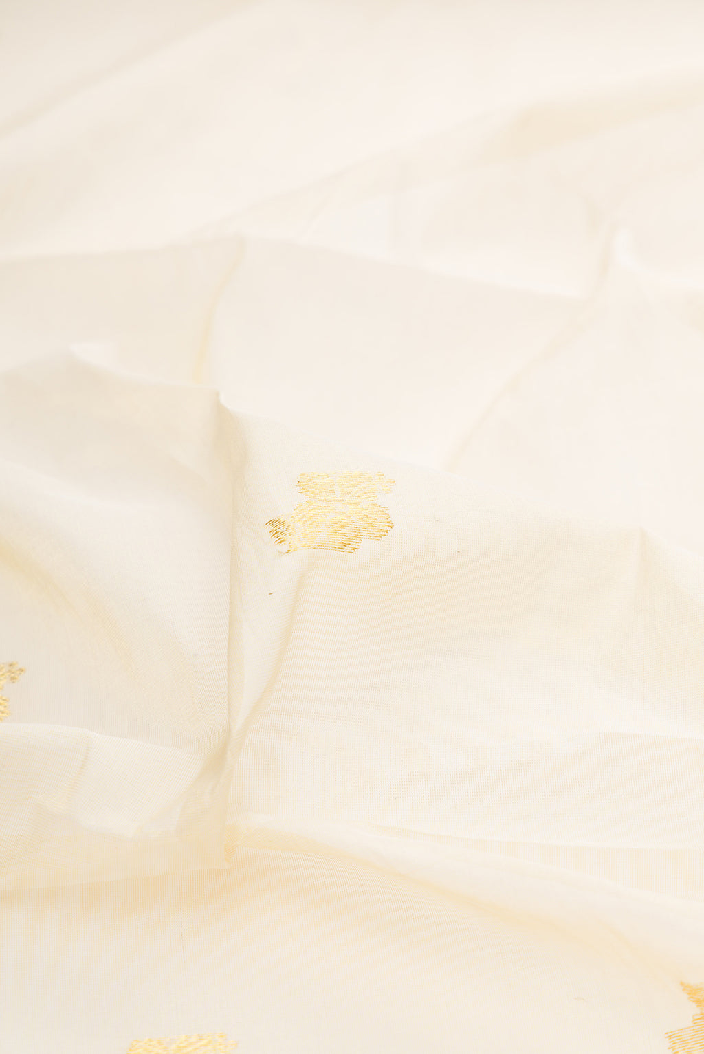 Close up of Off White Kerala Cotton Saree with Zari Butta on the body and Zari Border.  displaying folds