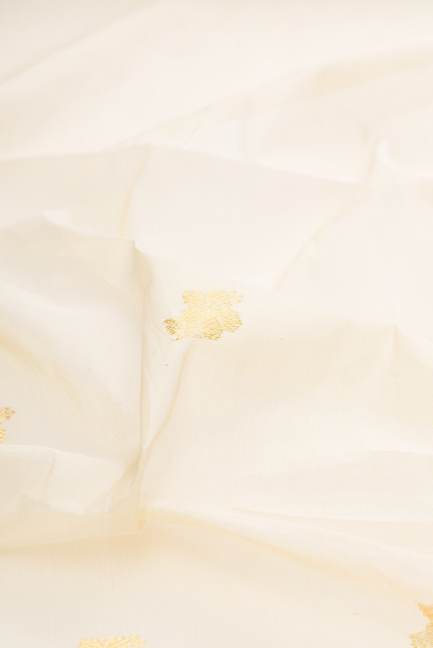 Close up of Off White Kerala Cotton Saree with Zari Butta on the body and Zari Border.  displaying folds
