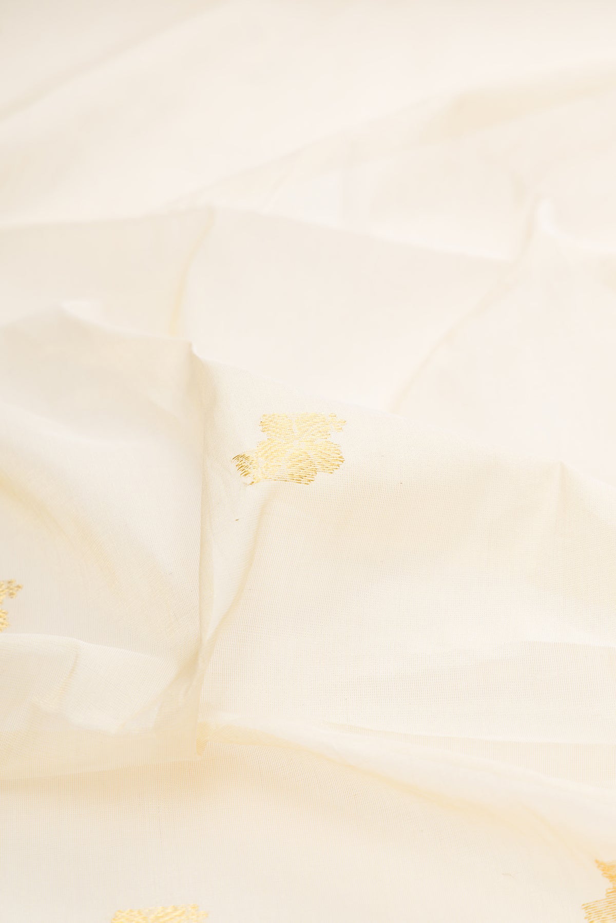 Close up of Off White Kerala Cotton Saree with Zari Butta on the body and Zari Border.  displaying folds