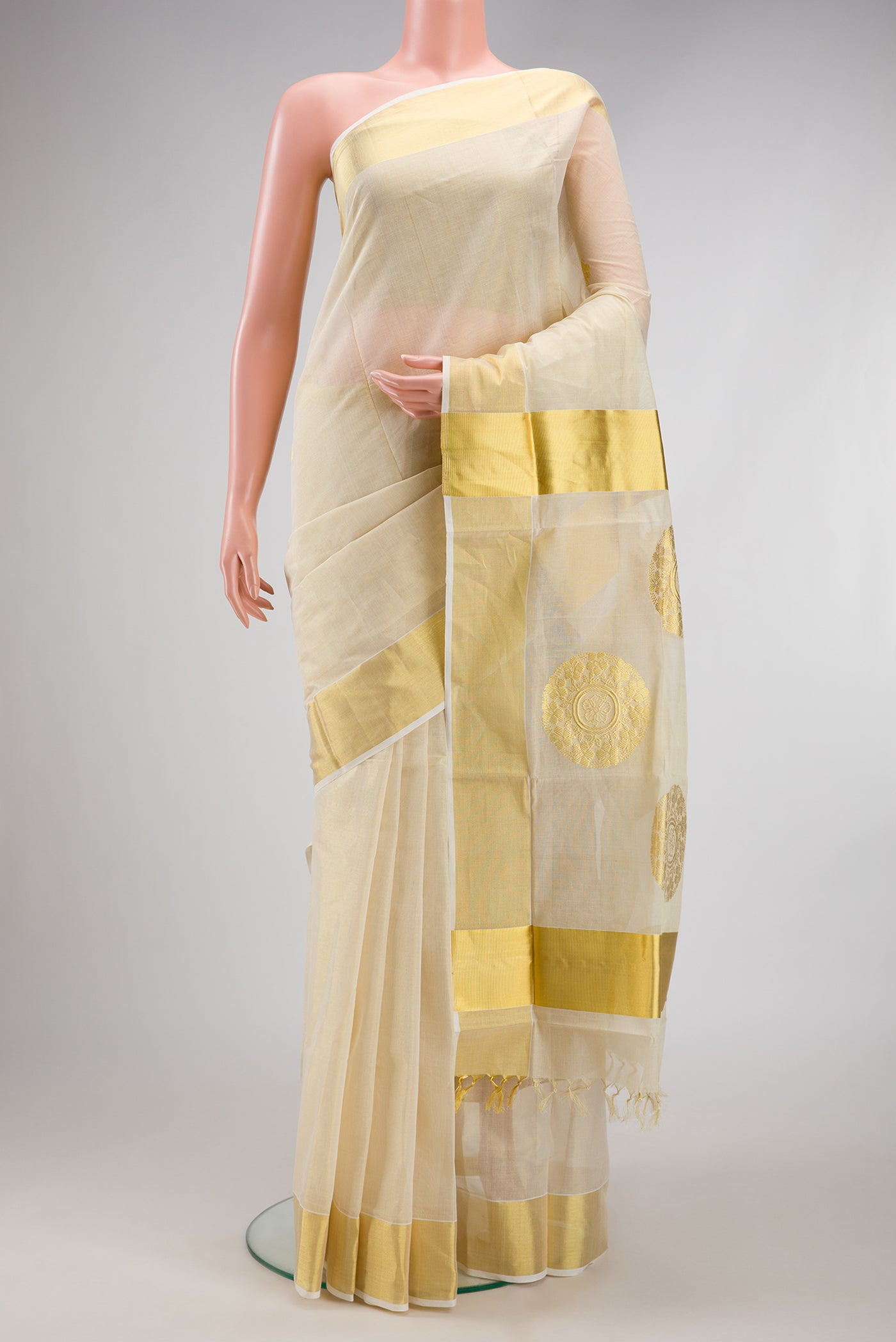 Off White Kerala Cotton Saree with Zari Butta on the body and Zari Border.  displayed on a mannequin