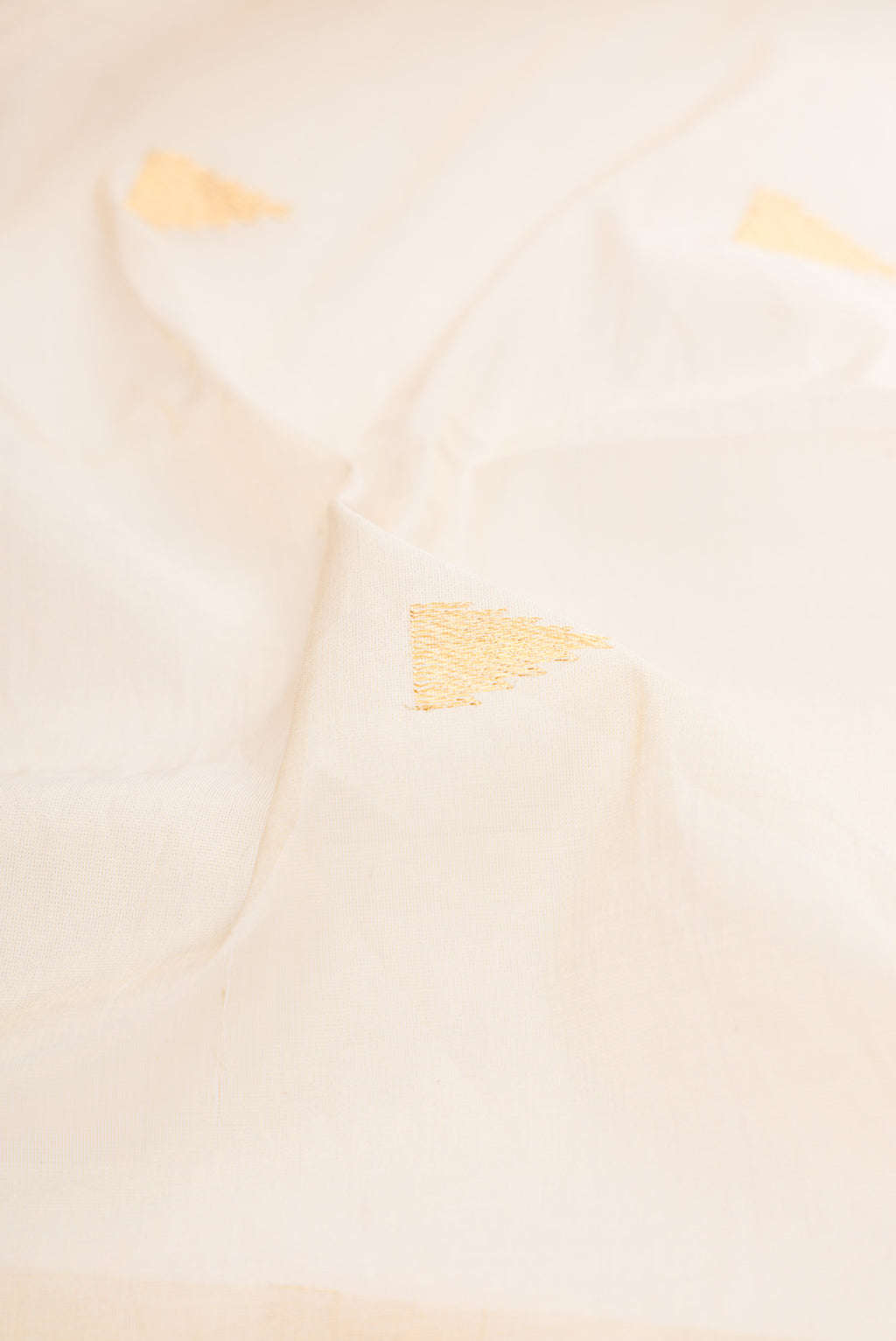 Close up of Off White Kerala Cotton Saree with Zari Butta on the body and Zari Border.  displaying folds