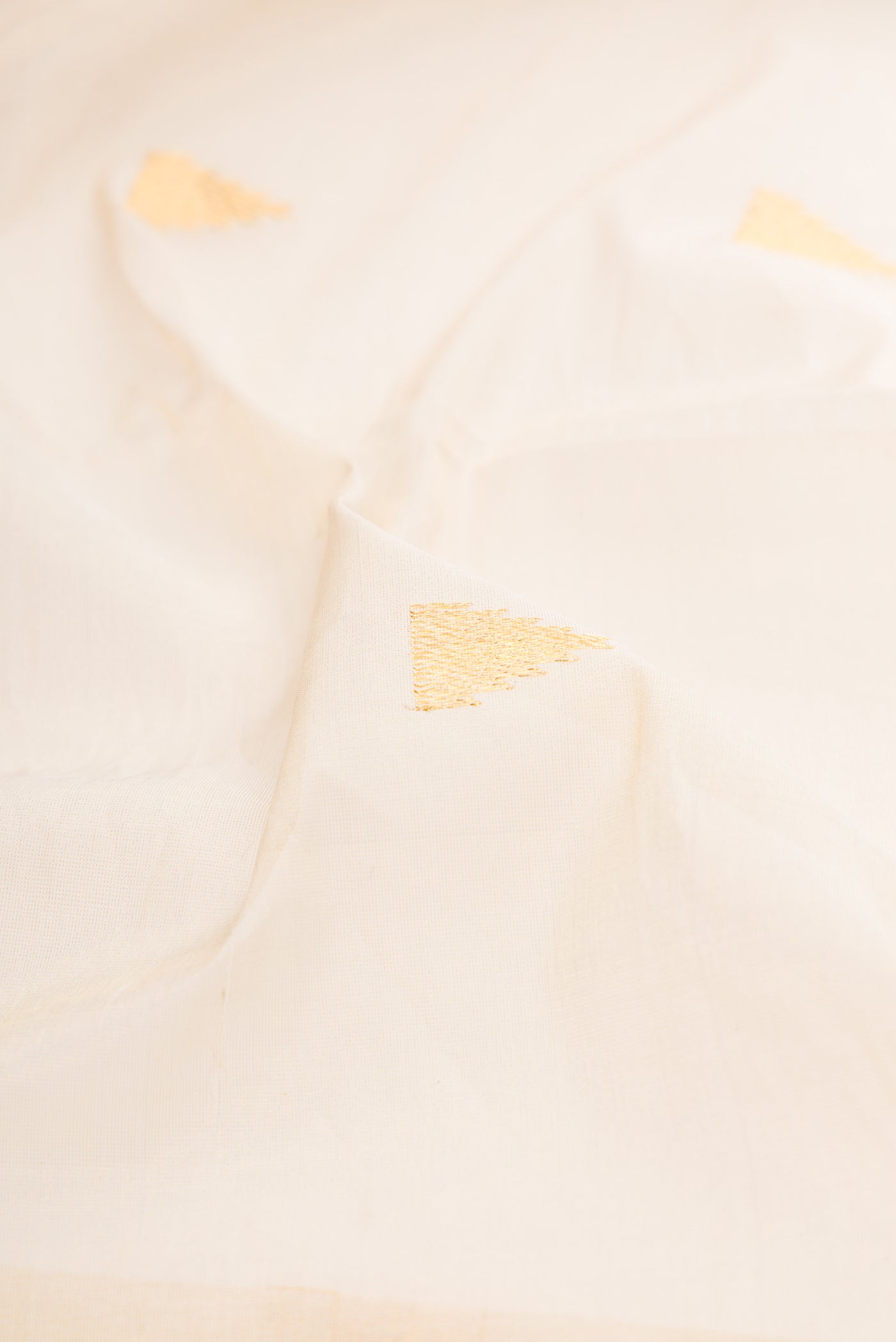 Close up of Off White Kerala Cotton Saree with Zari Butta on the body and Zari Border.  displaying folds