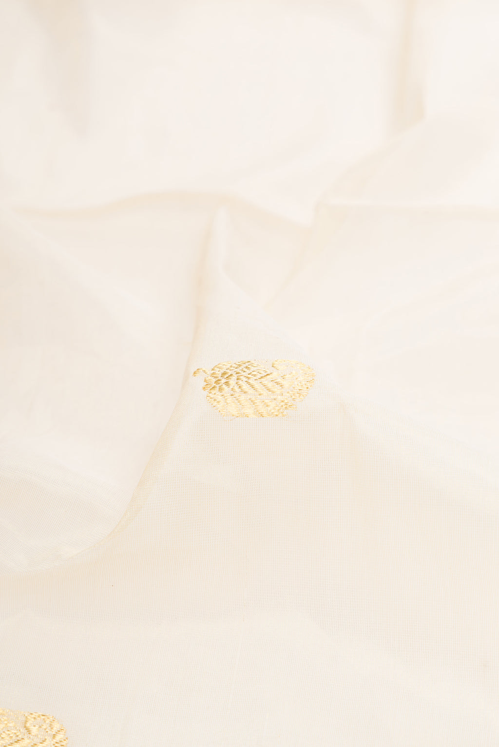 Close up of Off White Kerala Cotton Saree with Zari Butta on the body and Zari Border.  displaying folds