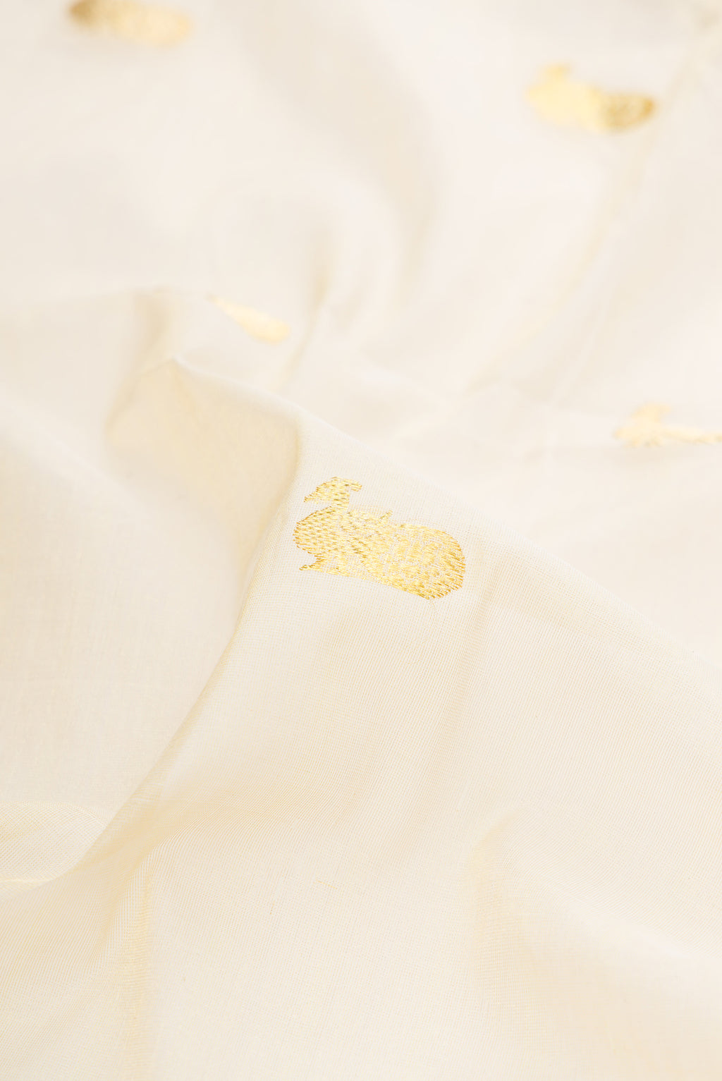 Close up of Off White Kerala Cotton Saree with Zari Butta on the body and Zari Border.  displaying folds