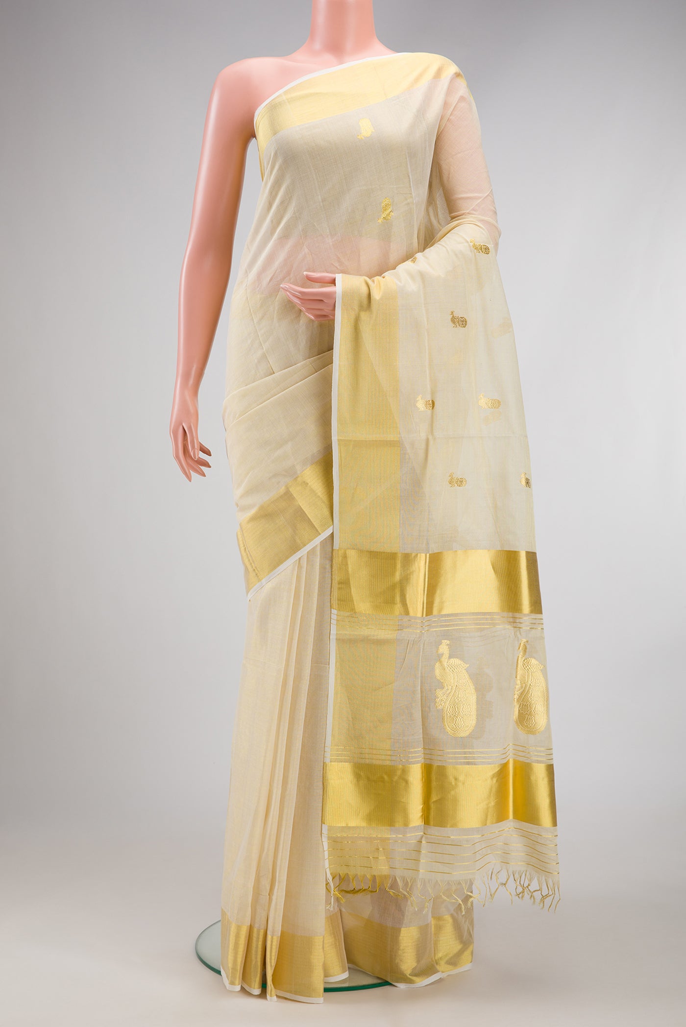 Off White Kerala Cotton Saree with Zari Butta on the body and Zari Border.  displayed on a mannequin