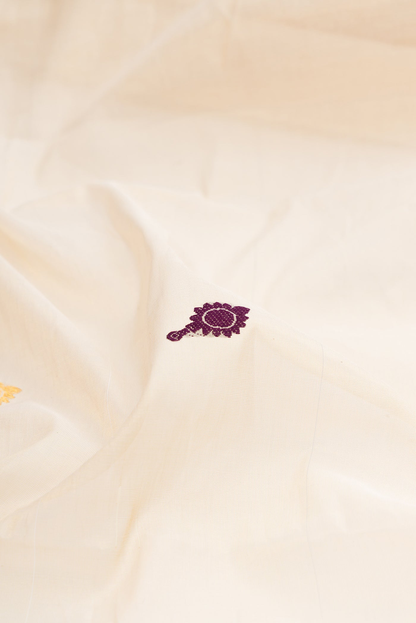 Close up of Off White Kerala Cotton Saree with Zari And Thread Butta on the body and Zari Border.  displaying folds