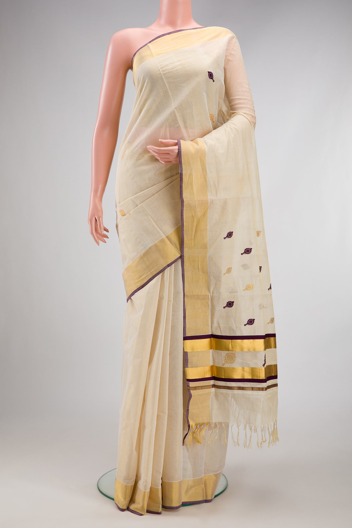Off White Kerala Cotton Saree with Zari And Thread Butta on the body and Zari Border.  displayed on a mannequin