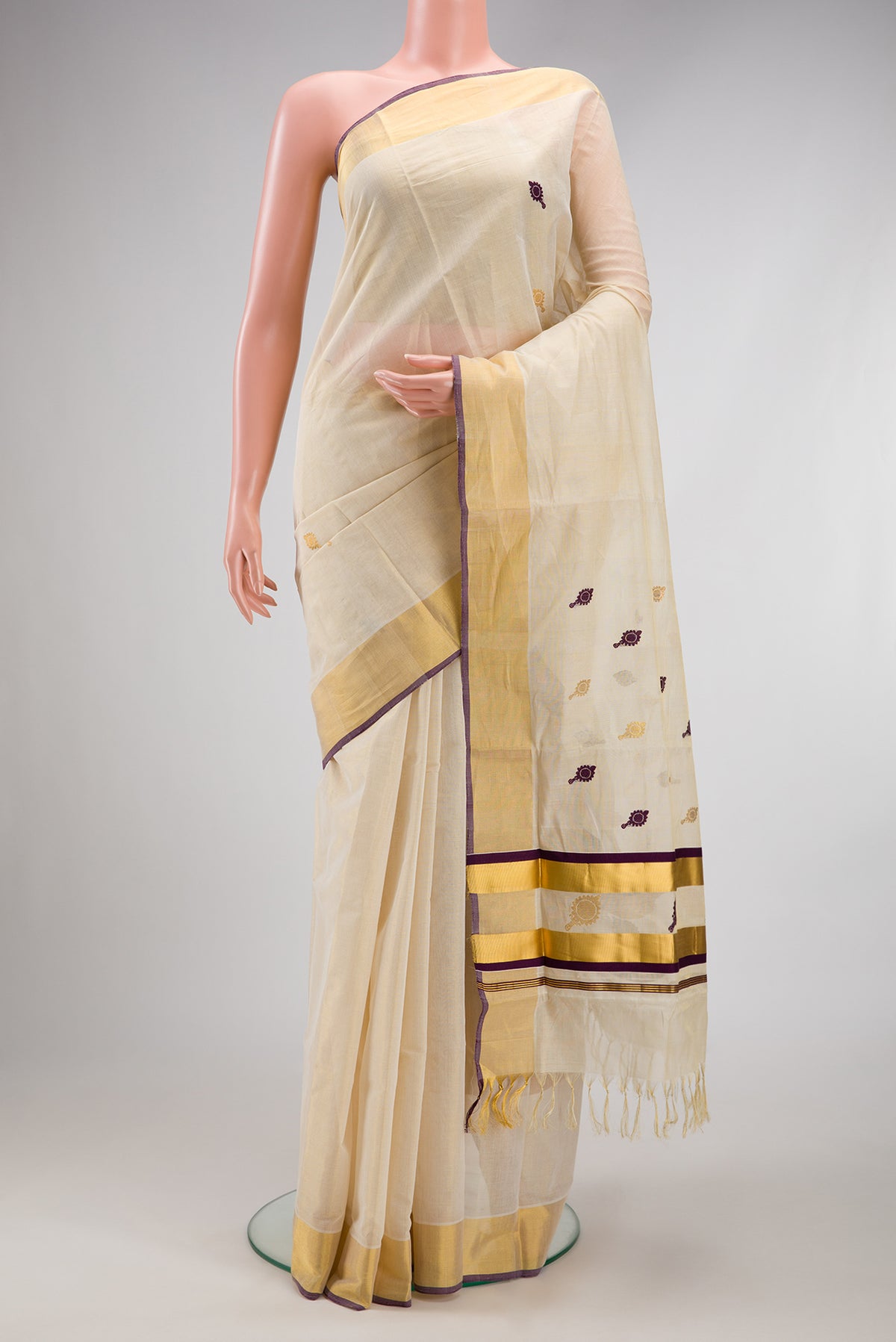 Off White Kerala Cotton Saree with Zari And Thread Butta on the body and Zari Border.  displayed on a mannequin