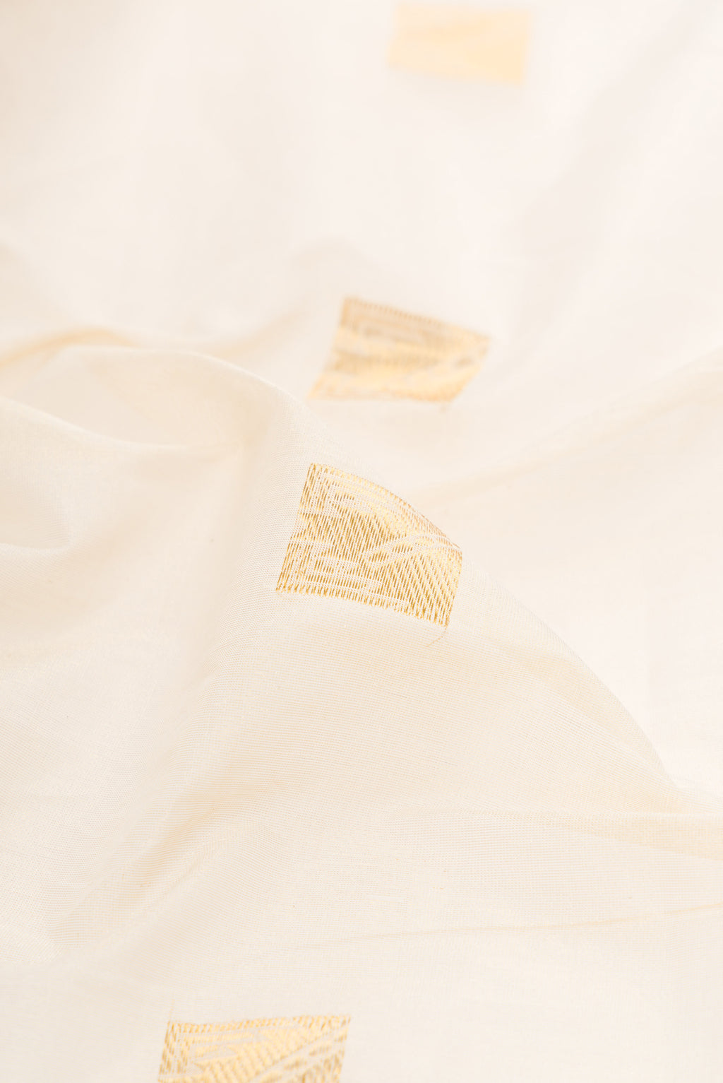 Close up of Off White Kerala Cotton Saree with Zari Butta on the body and Zari Border.  displaying folds