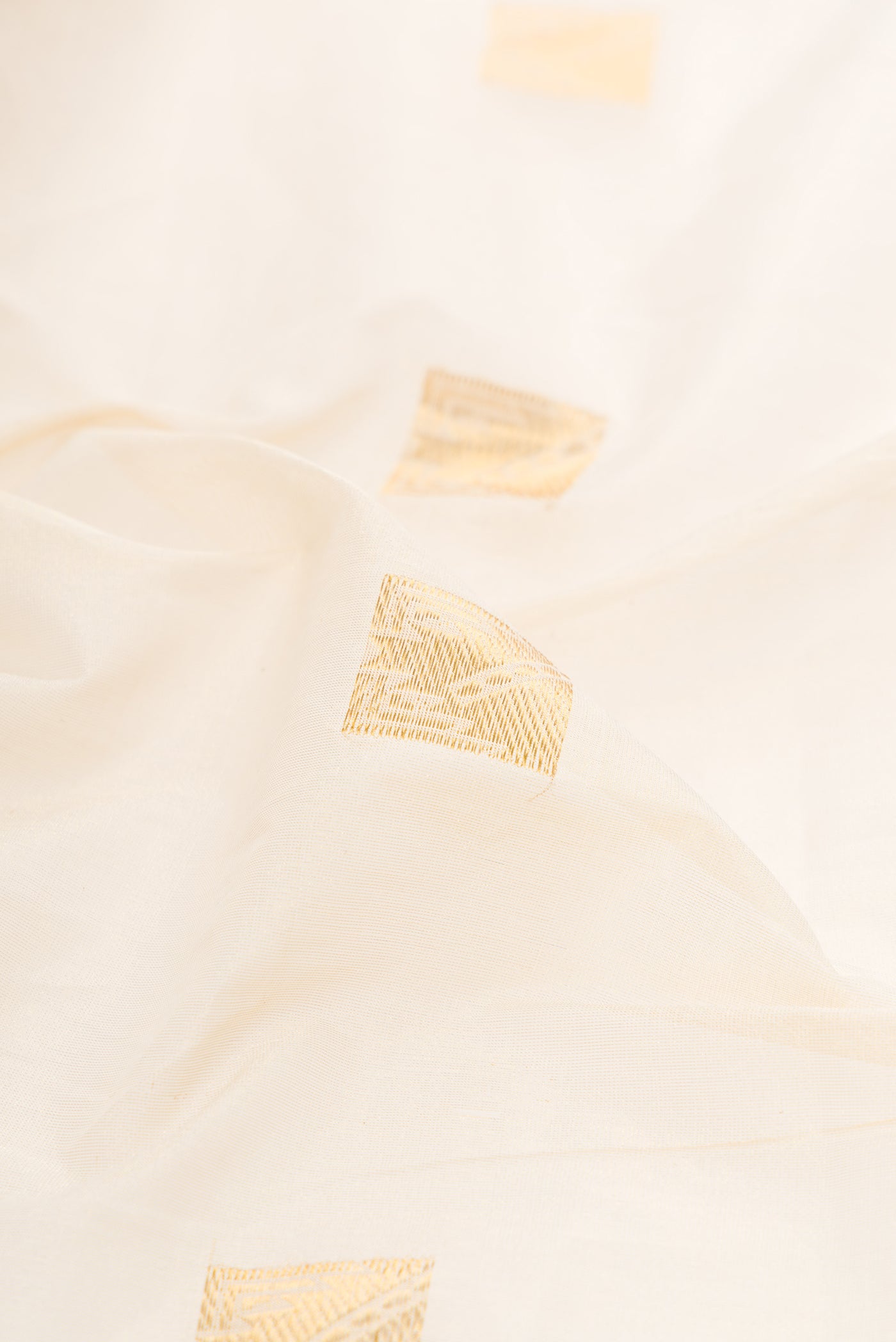 Close up of Off White Kerala Cotton Saree with Zari Butta on the body and Zari Border.  displaying folds