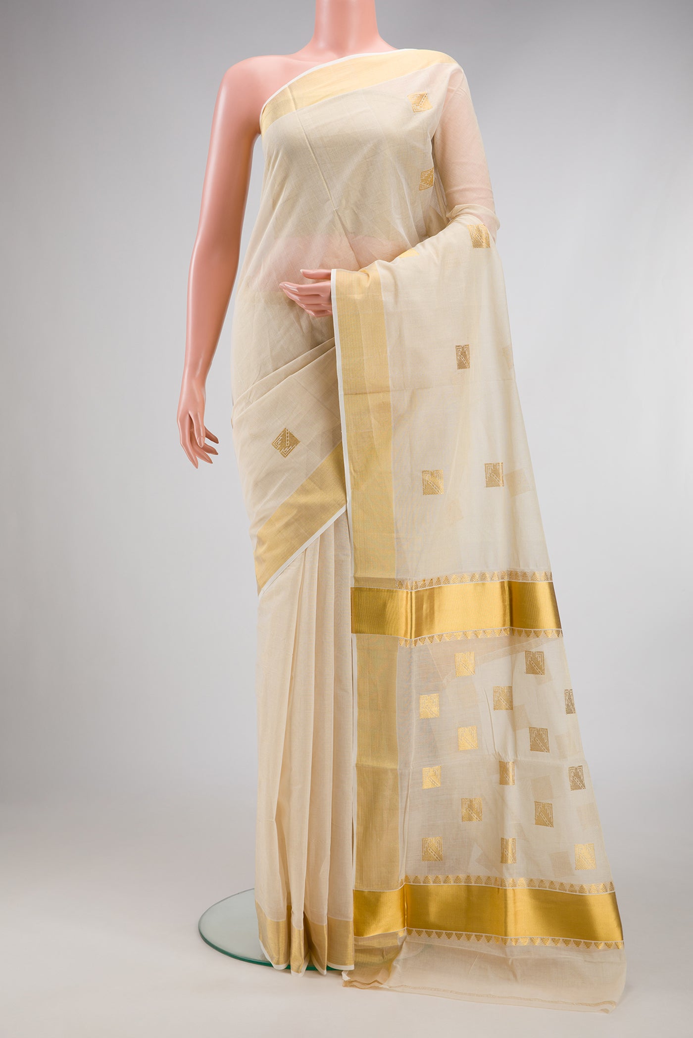 Off White Kerala Cotton Saree with Zari Butta on the body and Zari Border.  displayed on a mannequin