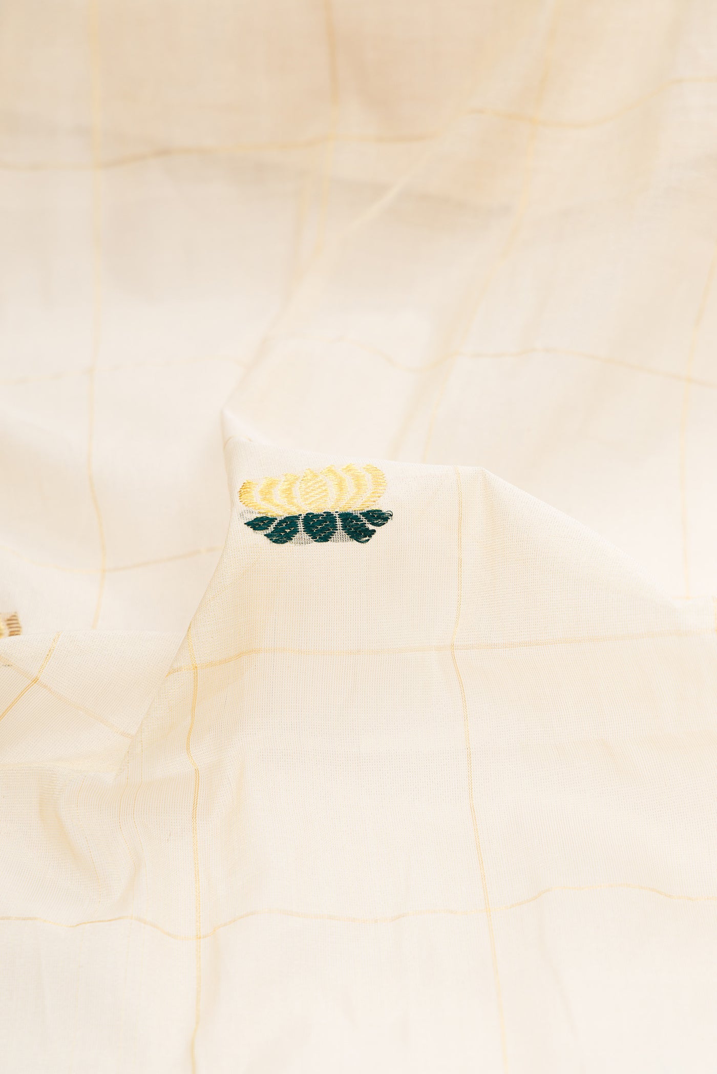 Close up of Off White Kerala Cotton Saree with Checked design on the body and Zari Border.  displaying folds