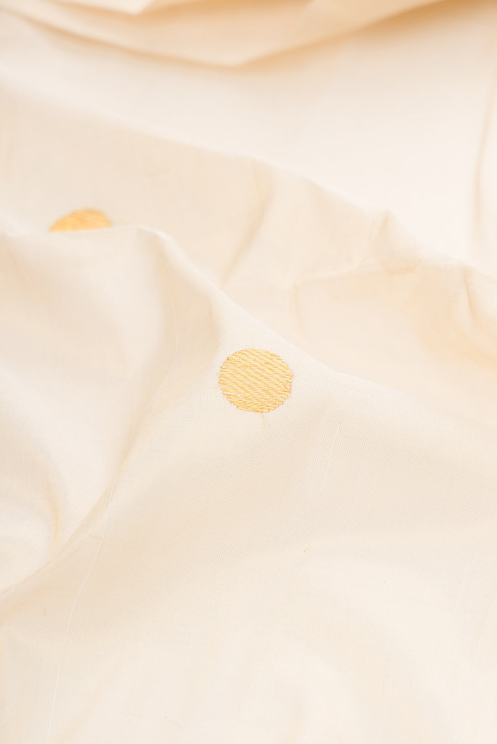 Close up of Off White Kerala Cotton Saree with Zari Butta on the body and Zari Border.  displaying folds