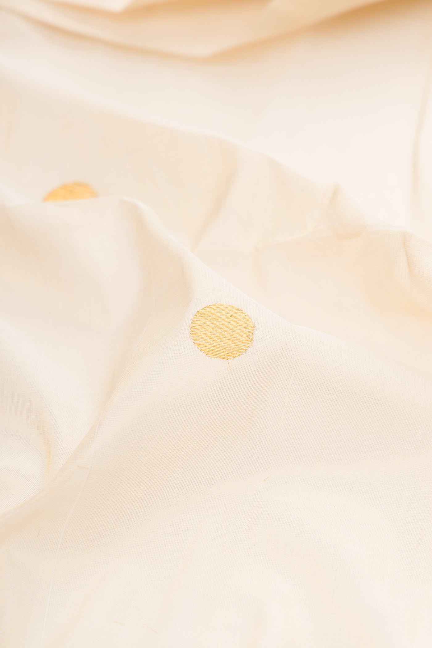 Close up of Off White Kerala Cotton Saree with Zari Butta on the body and Zari Border.  displaying folds