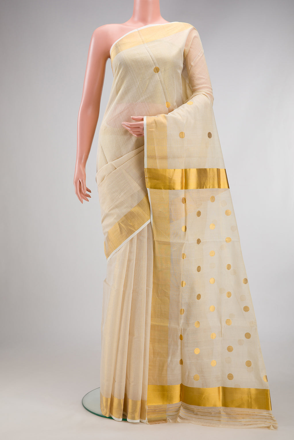 Off White Kerala Cotton Saree with Zari Butta on the body and Zari Border.  displayed on a mannequin