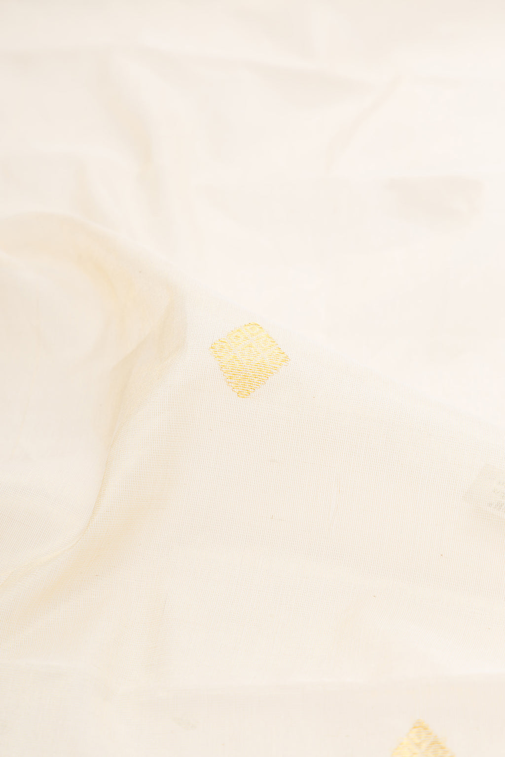 Close up of Off White Kerala Cotton Saree with Zari Butta on the body and Zari Border.  displaying folds